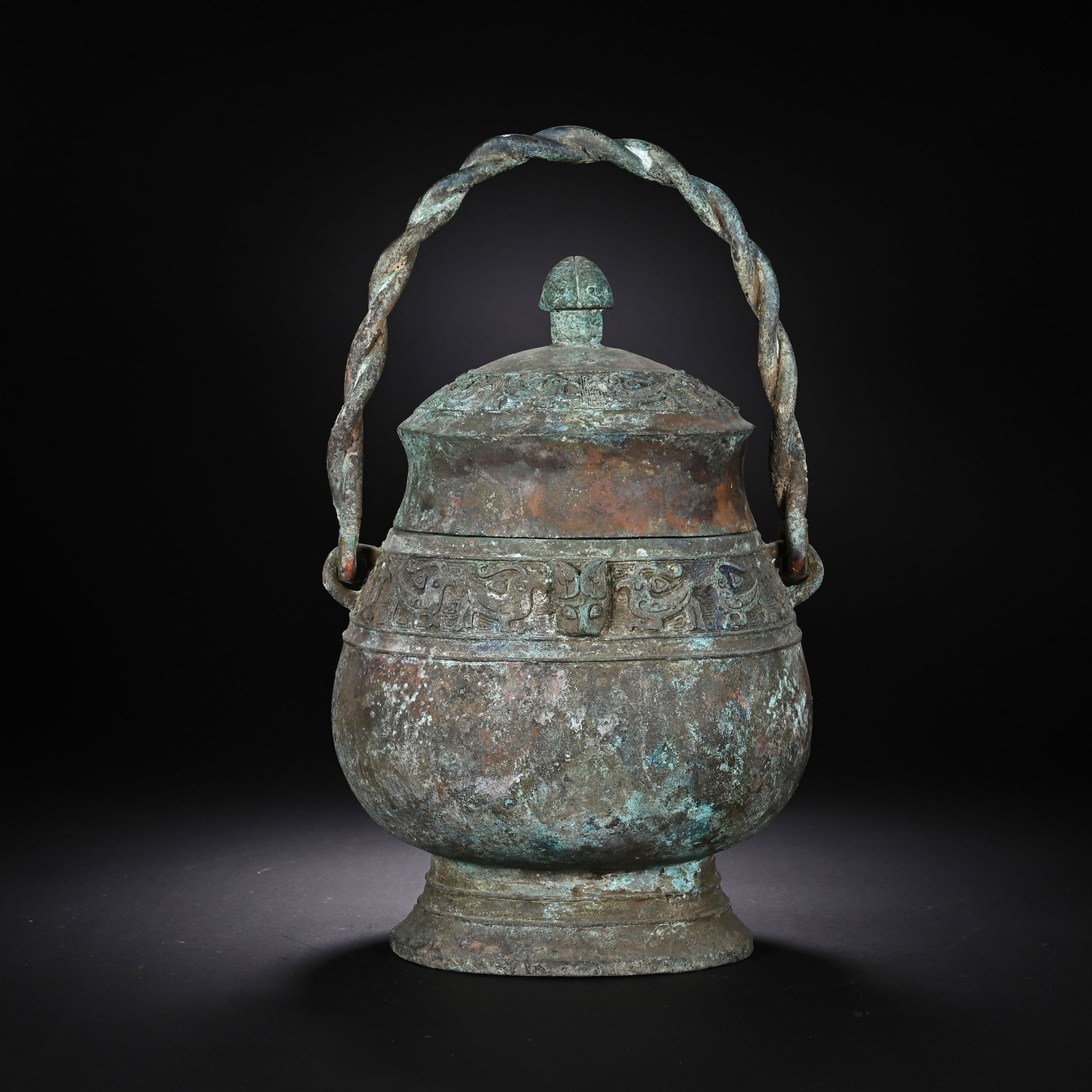 A CHINESE BRONZE YOU VESSEL: Standing 33 cm in height and 20 cm in width, this classic ritual you wine vessel bears layered verdigris and earthy patination accumulated over time across its textured exterior. A twisted braided han