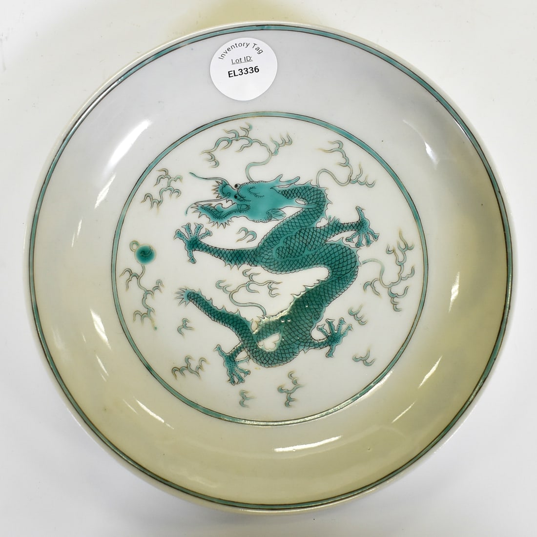 YONGZHENG FAMILLE VERTE DRAGON PLATE: Dimensions: 7" Diameter. A blue and red shallow plate. The center motif is that of a 5-toed dragon superimposed on a background of rouge-de-fer rolling waves. The exterior walls depict nine blue 5-toe