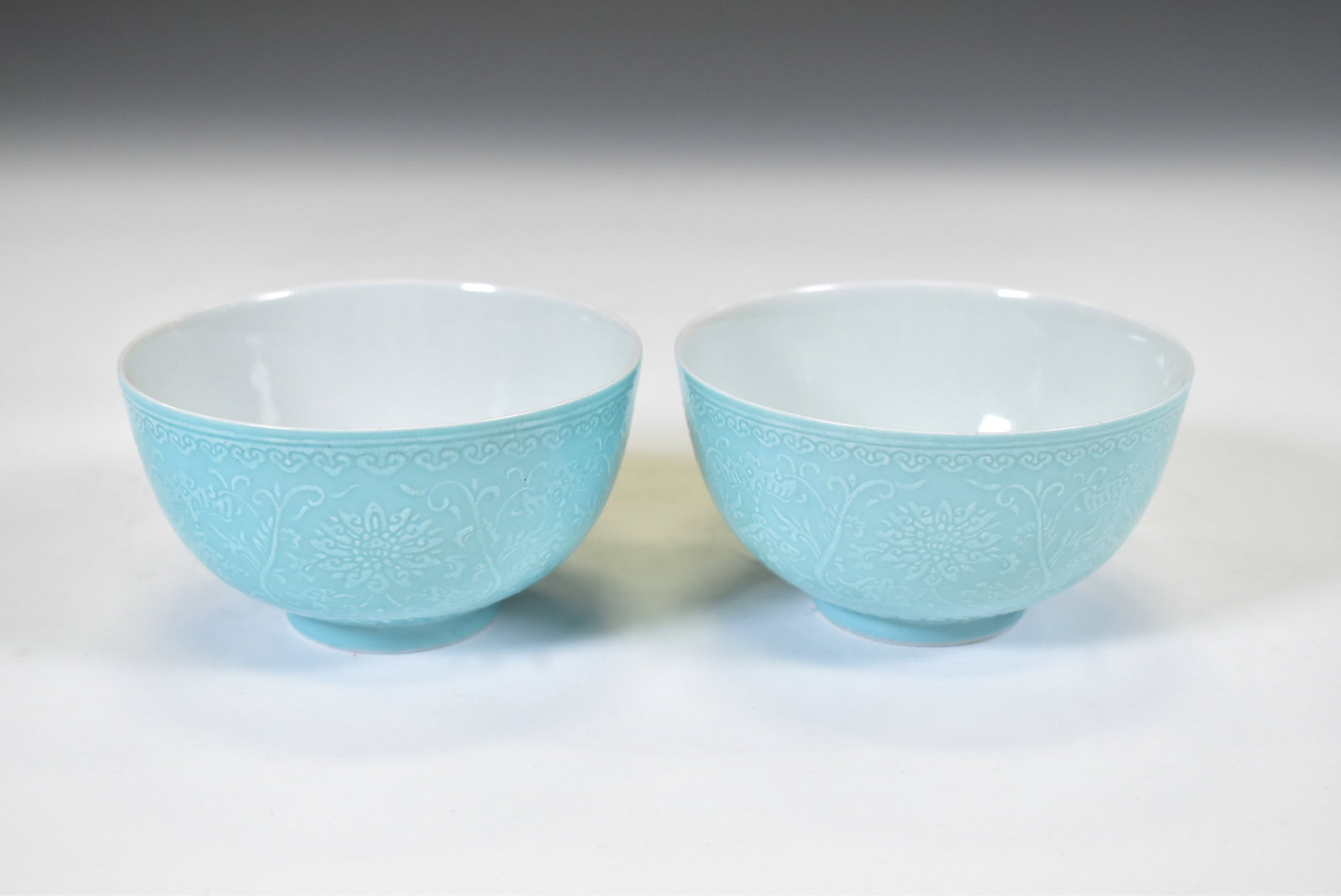 PAIR OF SKY BLUE GLAZED PORCELAIN BOWLS: Dimensions: 2.5"H x 4.5"H. A Fine Pair of Turquoise-Ground Carved Porcelain BowlsDelicately potted with thin, even walls and finished in a soft turquoise glaze, each bowl is decorated on the exterior 