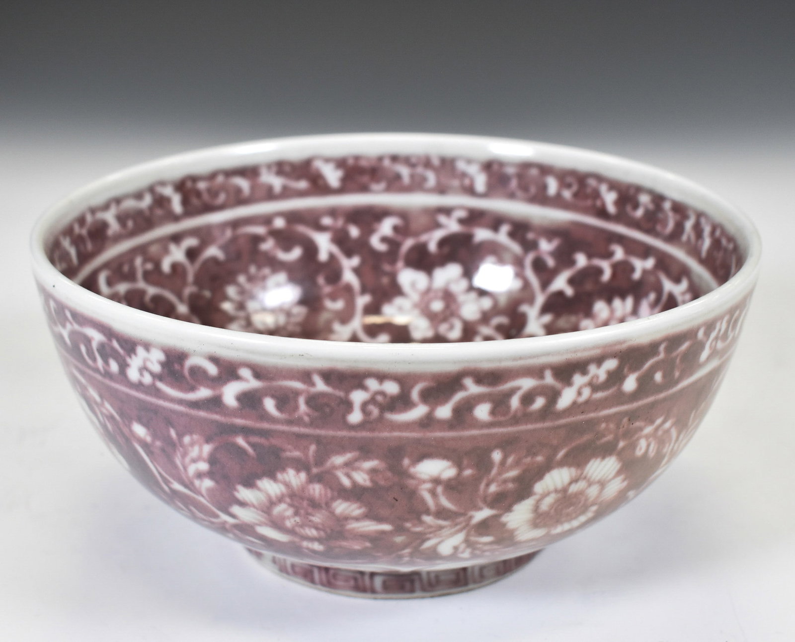 MING WRAPPED FLORAL RED UNDERGLAZED BOWL: Dimensons: 3.875in H x 8.25in W x 8.25in D. Chinese Ming Dynasty Red & white Underglazed Wrapped Floral Motif Porcelain Bowl. The porcelain potted with a shallow body, slight deep, close mouth rim, ra