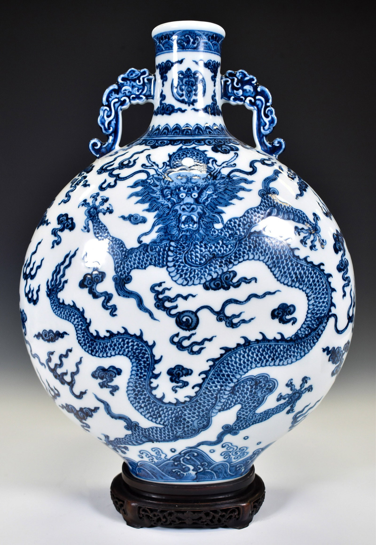 QNALONG BLUE & WHITE DRAGON PORCELAIN MOON VASE ON STAND: Dimensions: 19"H x 12.5"W . Chinese Qing Dynasty Qianlong Blue and White Dragon Porcelain Moon Flat Bottle Vase On Carved Hardwood Stand. The porcelain potted in moon vase, thick and tall, globular mo