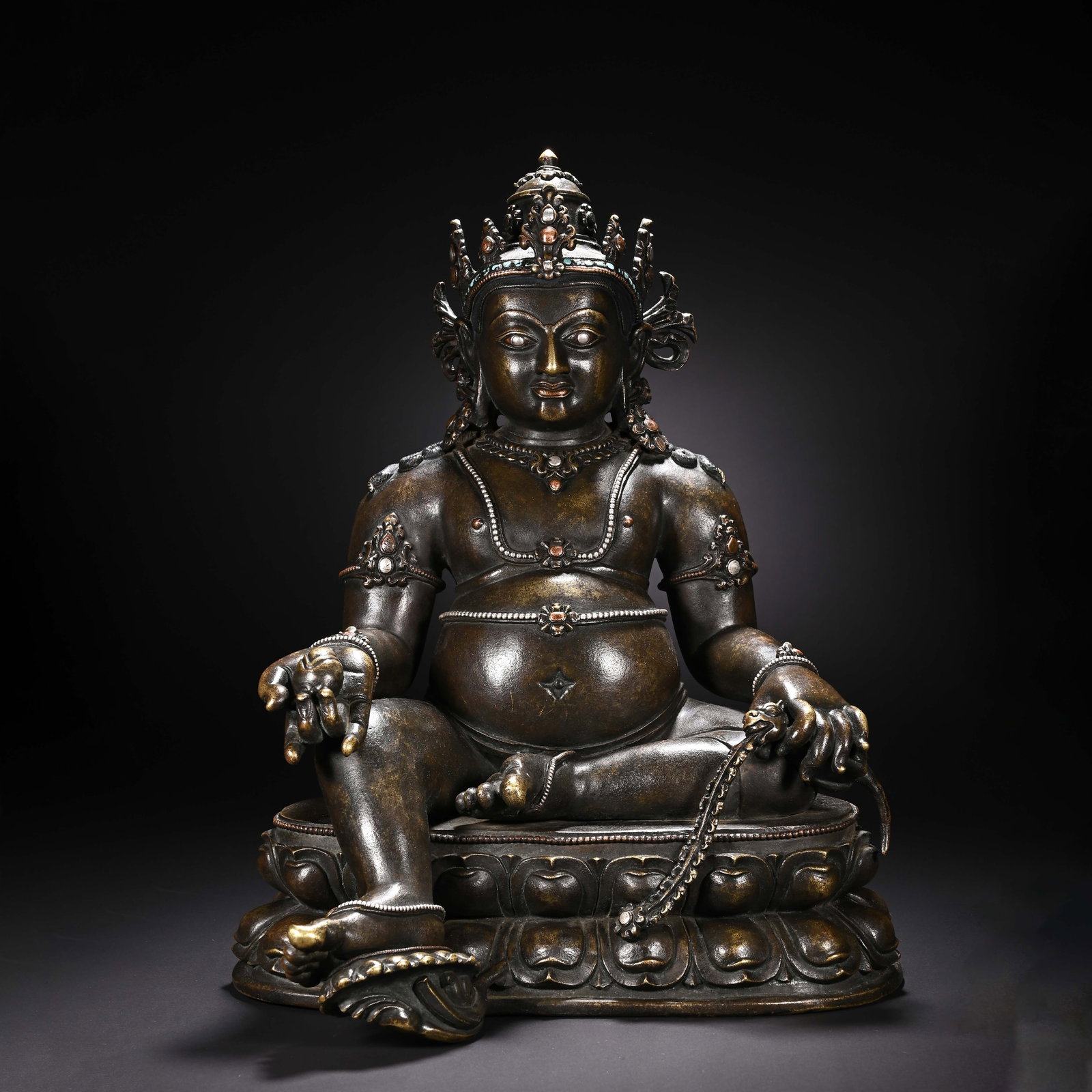 A CHINESE ALLOY COPPER JAMBHALA STATUE: Measuring 39 cm in height and 28 cm in width, this finely cast alloy copper sculpture depicts seated Yellow Jambhala, the revered Buddhist deity of prosperity. The deity boasts characteristic rounded 