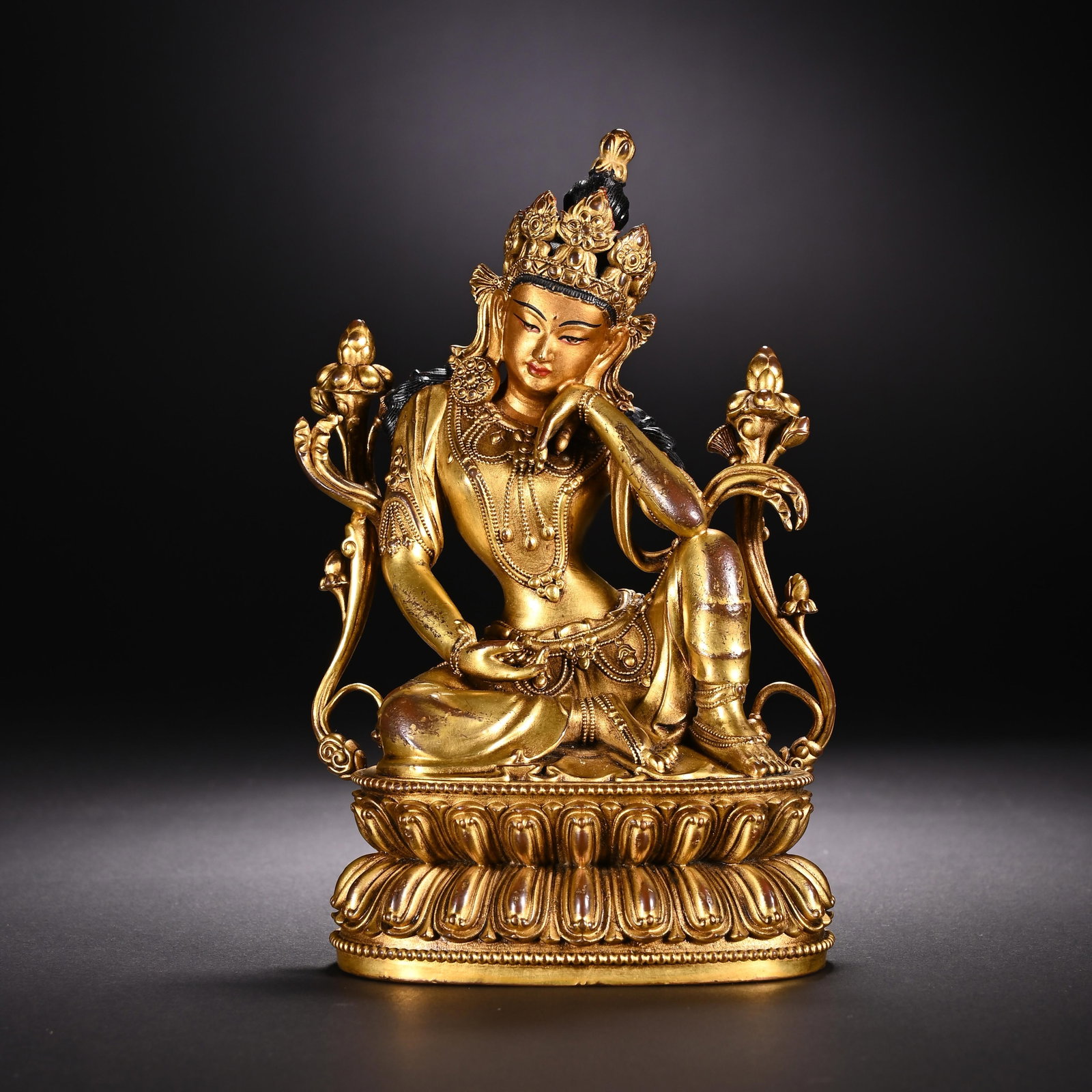 A CHINESE GILT BRONZE BODHISATTVA STATUE: This finely cast Chinese gilt-bronze figure depicts a pensive bodhisattva seated in a relaxed, contemplative pose atop an intricately moulded double lotus pedestal. Adorned with elaborate tiara, layer
