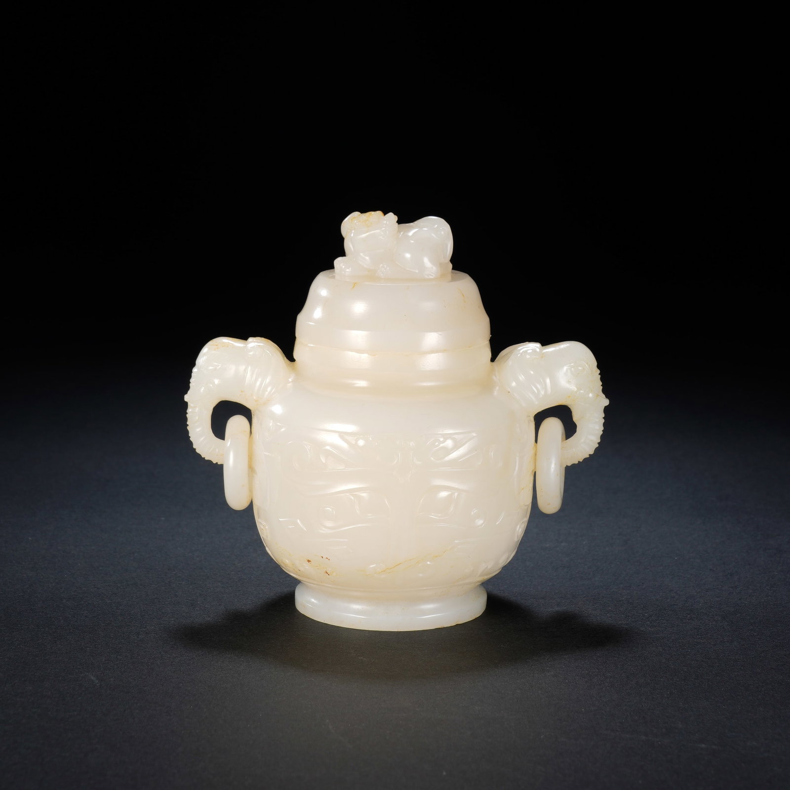 A CHINESE WHITE JADE TWO HANDLED CENSER: Masterfully carved from lustrous white jade, this elegant lidded censer features a pair of finely sculpted elephant-head handles fitted with freely moving suspension rings. A recumbent mythical beast 
