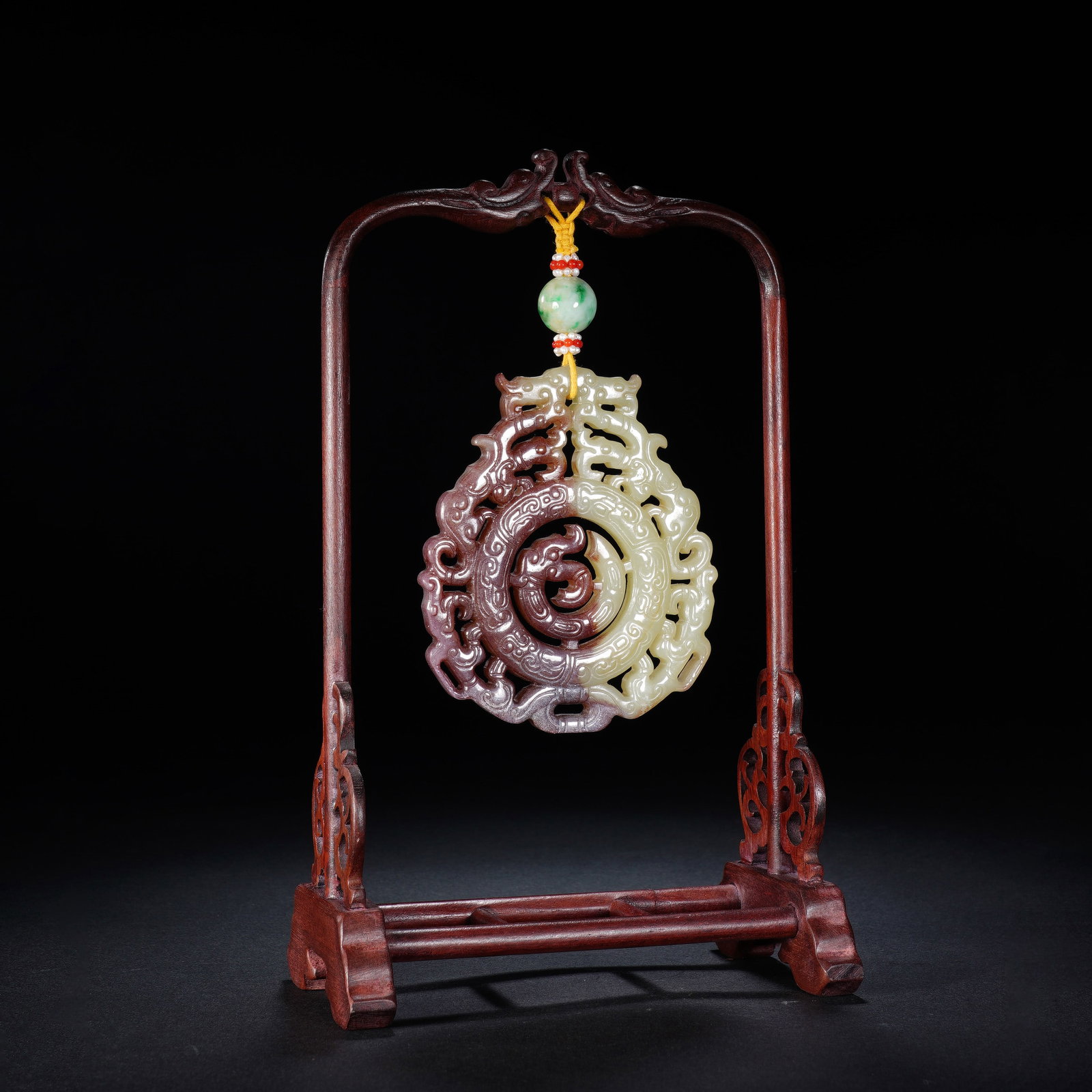 A CHINESE TWIN DRAGON JADE PENDANT: This intricately pierced jade pendant features elegantly carved twin dragons, with striking dual-toned jade patination that blends warm brownish hues and pale creamy tones across its openwork surface.