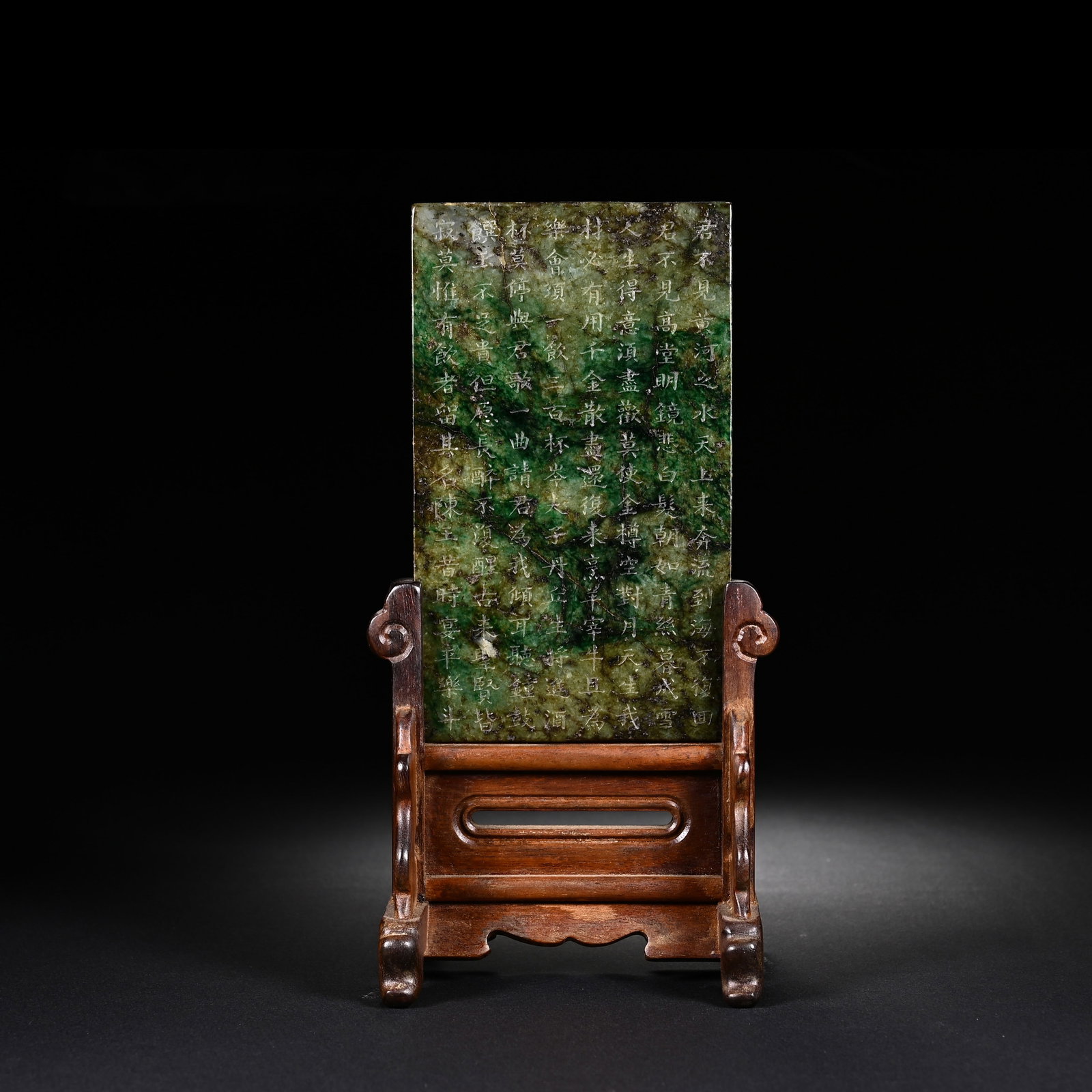 A CHINESE JADEITE TABLE SCREEN: Measuring 19 cm in height and 9 cm in width, this refined desk insert screen features a rectangular jadeite plaque marked by rich mottled emerald-green hues alongside natural darker veining across its