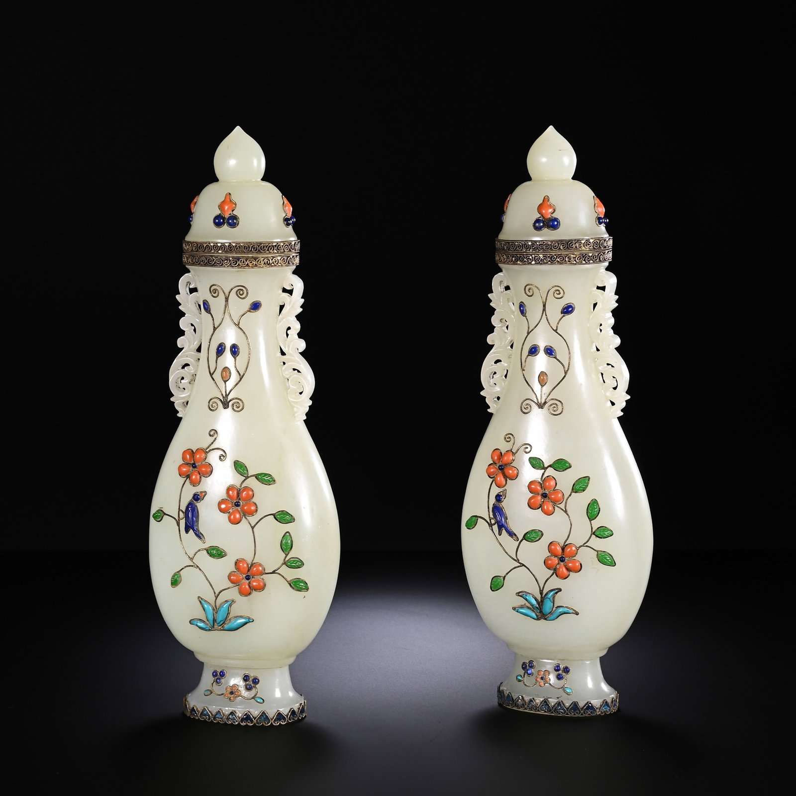 A PAIR OF CHINESE INLAID HETIAN JADE VASES: Fashioned from creamy polished Hetian jade, this matched pair of lidded display vases exhibits elegant, slender pear-shaped silhouettes. Openwork scrolling handles adorn each neck, while vibrant hards
