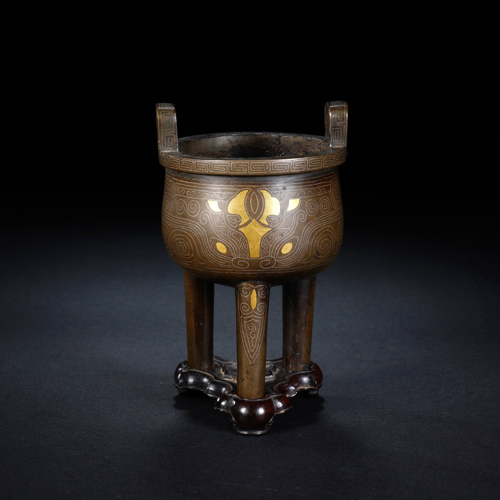A CHINESE SILVER INLAID TRIPOD BRONZE CENSER: This elegant tripod bronze censer is equipped with two upright rectangular upright handles, and its rim is decorated with neatly rendered repeating key-fret borders. Intricate silver wire inlays trace