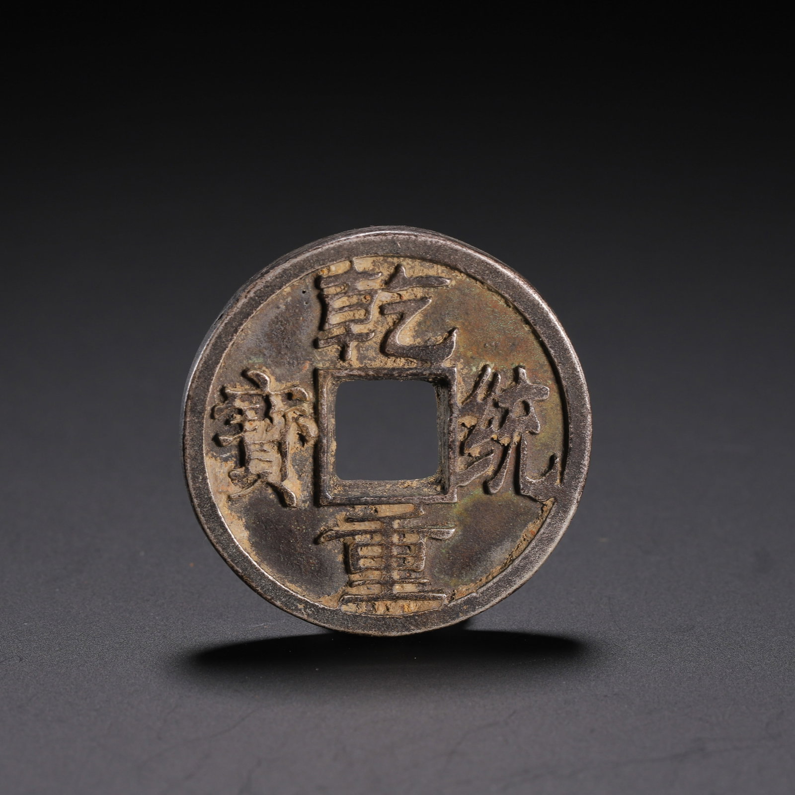 A CHINESE SILVER COIN: With a diameter of 4 cm and a weight of 20 grams, this circular silver coin adopts the classic traditional layout with a neat square hole cut through its centre. Four raised Chinese characters are sym