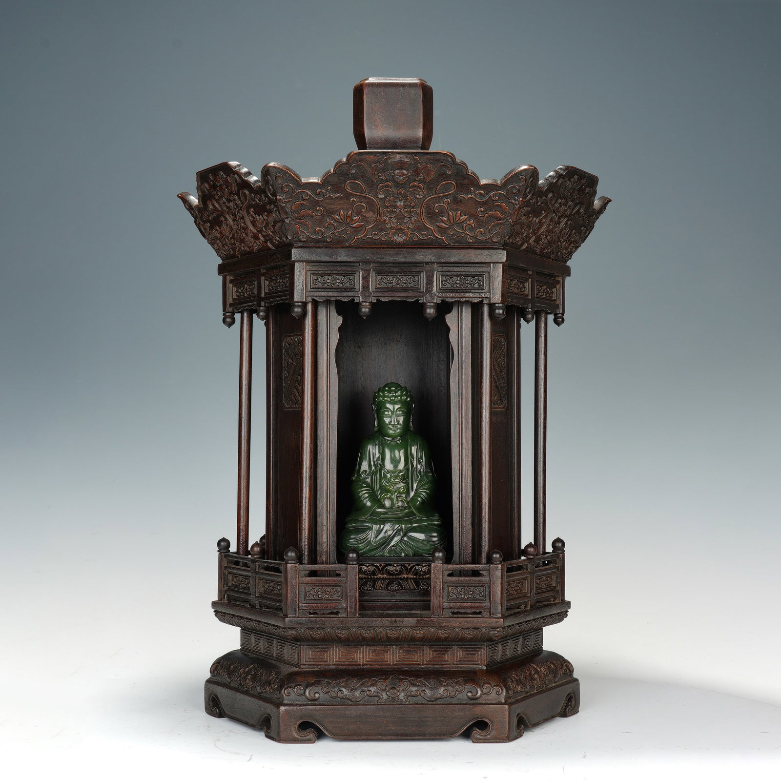 A CHINESE ZITAN NICHE WITH SPINACH JADE SHAKYAMUNI: The seated Shakyamuni jade statuette measures 8.5 x 4.5 x 14 cm, while the hexagonal zitan shrine reaches overall dimensions of 35 x 30 x 31 cm, with a combined weight of 654 grams. Deep-green polishe