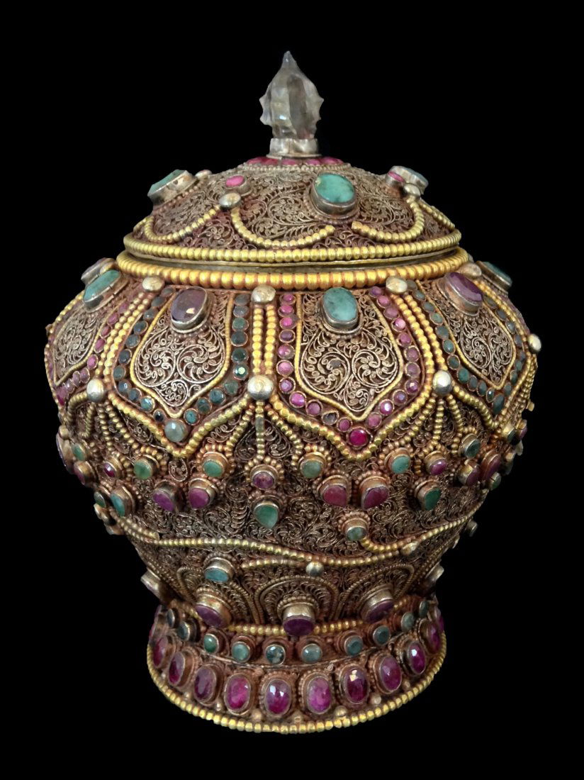 Chinese Silver Filligree Jewelry Jar: A Jewel and Filigree silver Temple Jar, ovoid body raised on circular foot, domed cover with quartz finial carved in vajra form, faceted ruby and emerald inset copper filigree. Measure: 6 1/8" height,