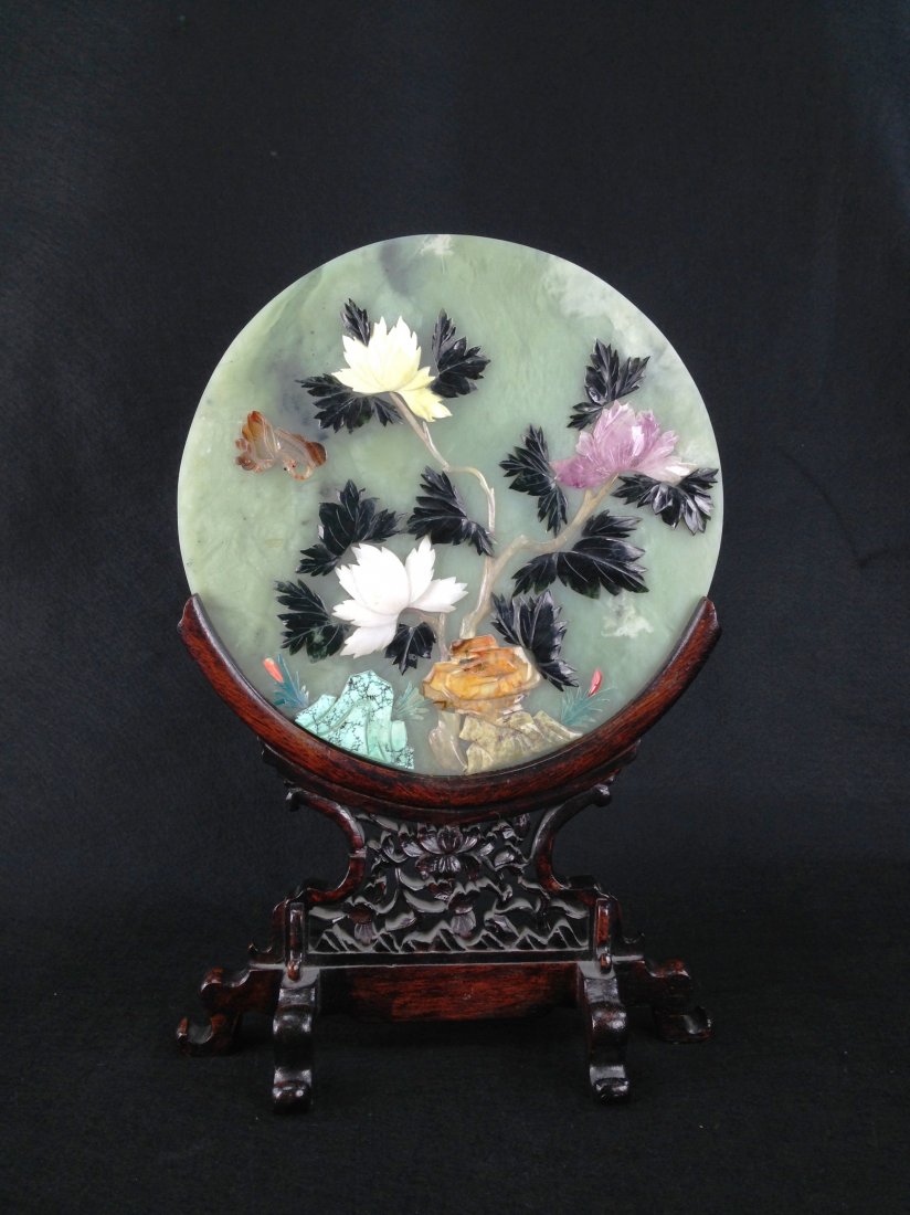 A CHINESE CARVED JADE AND STONE TABLE SCREEN: Â screen with turquoise, malachite, jade and other stones set onto a circular celadon plaque, verso with gilt painted scene depicting two birds on a leafy branch, 13 in., on a well-carved calamander