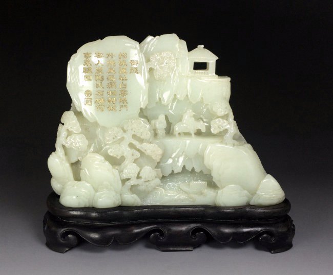 A LARGE CARVED WHITE JADE MOUNTAIN: Of irregular upright section, one side is well carved in high relief with a scene of two scholars with undercut trunk, one sage is riding an ox, while a follower are preparing for ceremonial offering,