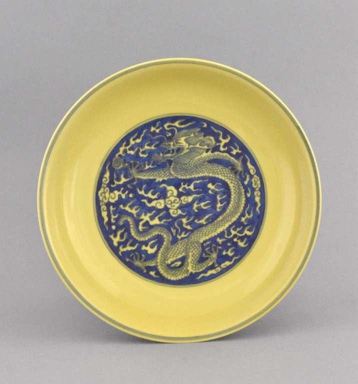 FAMILLE JAUNE DRAGON PLATE, YONGZHENG MARK: The shallow plate having the center interior decorated in cobalt blue hand painting depicted enormous imperial dragon soaring between flames and clouds in the pursuit of the flaming pearl. The rim lef