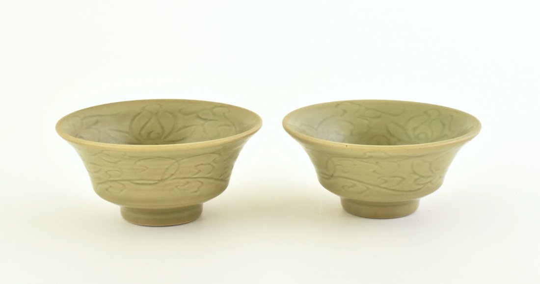 PAIR OF LONGQUAN CELADON BOWLS: Chinese Ming LongQuan celadon porcelain bowl. Of deep vessel body, with simply flared rim, raised on the concave footed base. The exterior is carved with rococo foliage in shallow relief revealing the