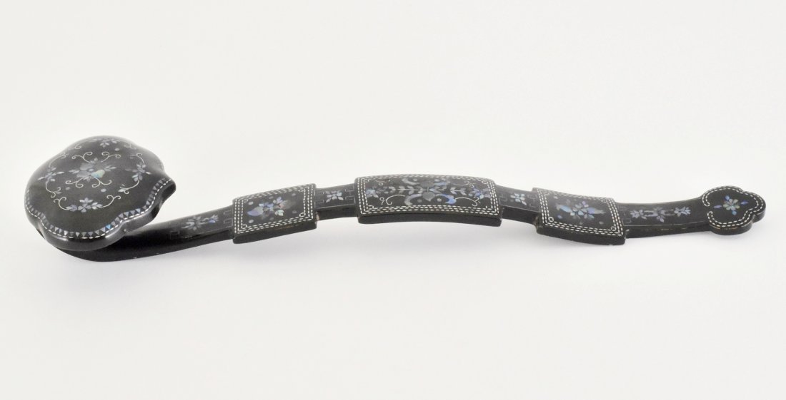 MOTHER OF PEARLS INLAID LACQUERED RUYI SCEPTER: In form of an arched wand, with three rectangular plaques flanked on the handle, beneath a ruyi shaped head. The exterior decorated with mother of pearls inlaid in floral motifs against ebony lacquere