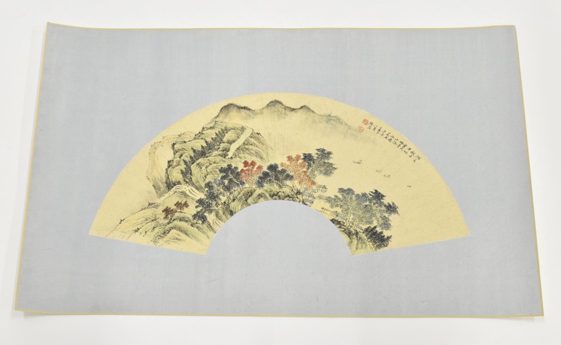 CHINESE WATERCOLOR FAN PAINTING OF LANDSCAPE: A Chinese watercolor fan painting, depicting panoramic of waterside within misty mountainous landscape scene. Showing theme poems inscription on top right followed by an iron-red signature seal. Matte