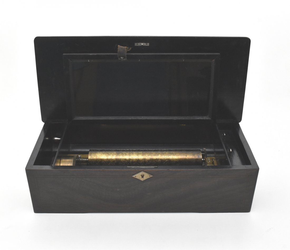 SWISS MAHOGANY INLAID CYLINDRICAL MUSIC BOX: An antique wooden music box in good working condition that plays six songs. Wooden case has a beautiful inlay in a variety of wood types. No key present but box is unlocked. Slight loss to inlay to si