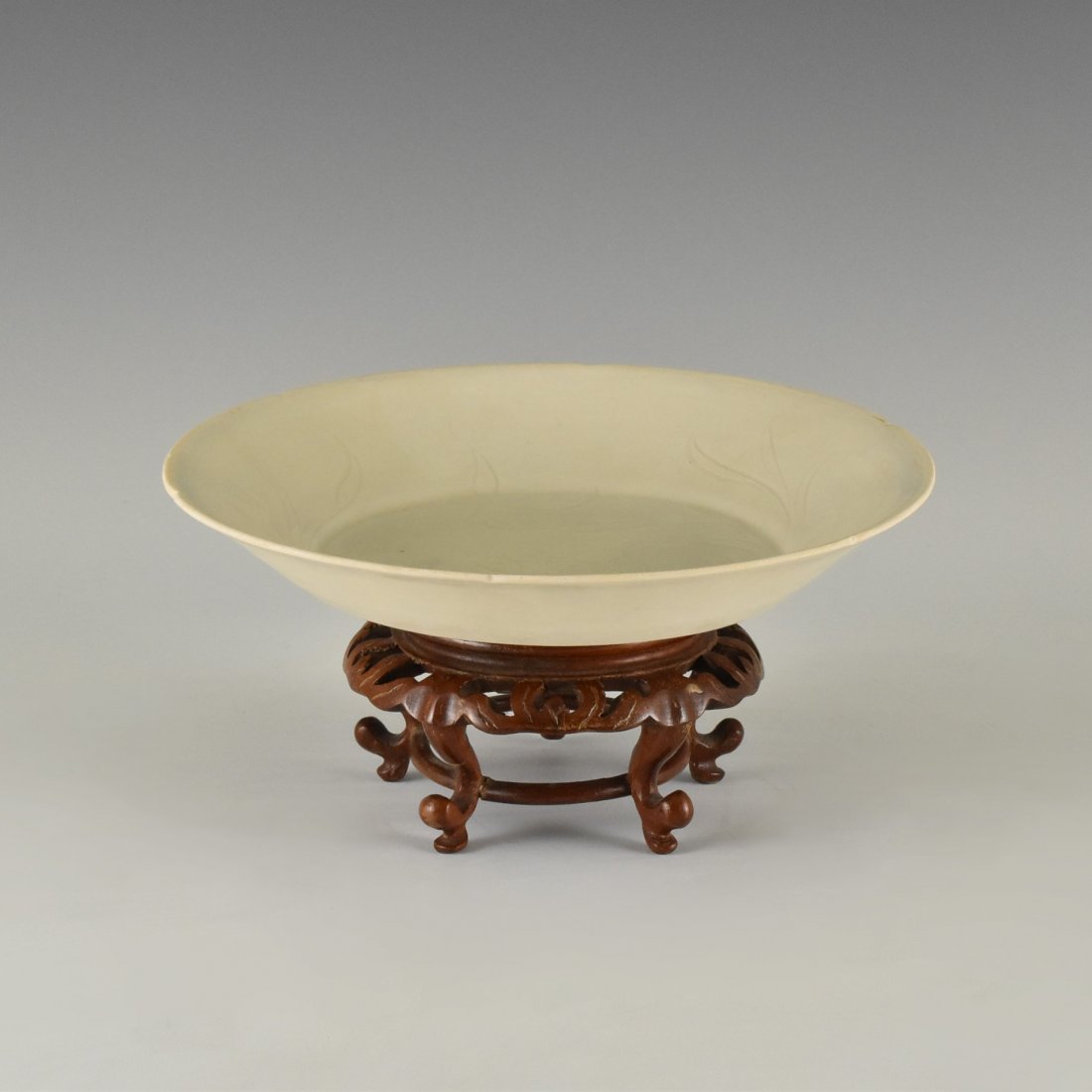 GEESE MOTIF DING-TYPE PLATE ON STAND: The plate having shallow body, with steep slightly rounded sides toward the quatrefoil flori-form petal rim, rising from a wide central body upon a countersunk foot base. The central interior carved i