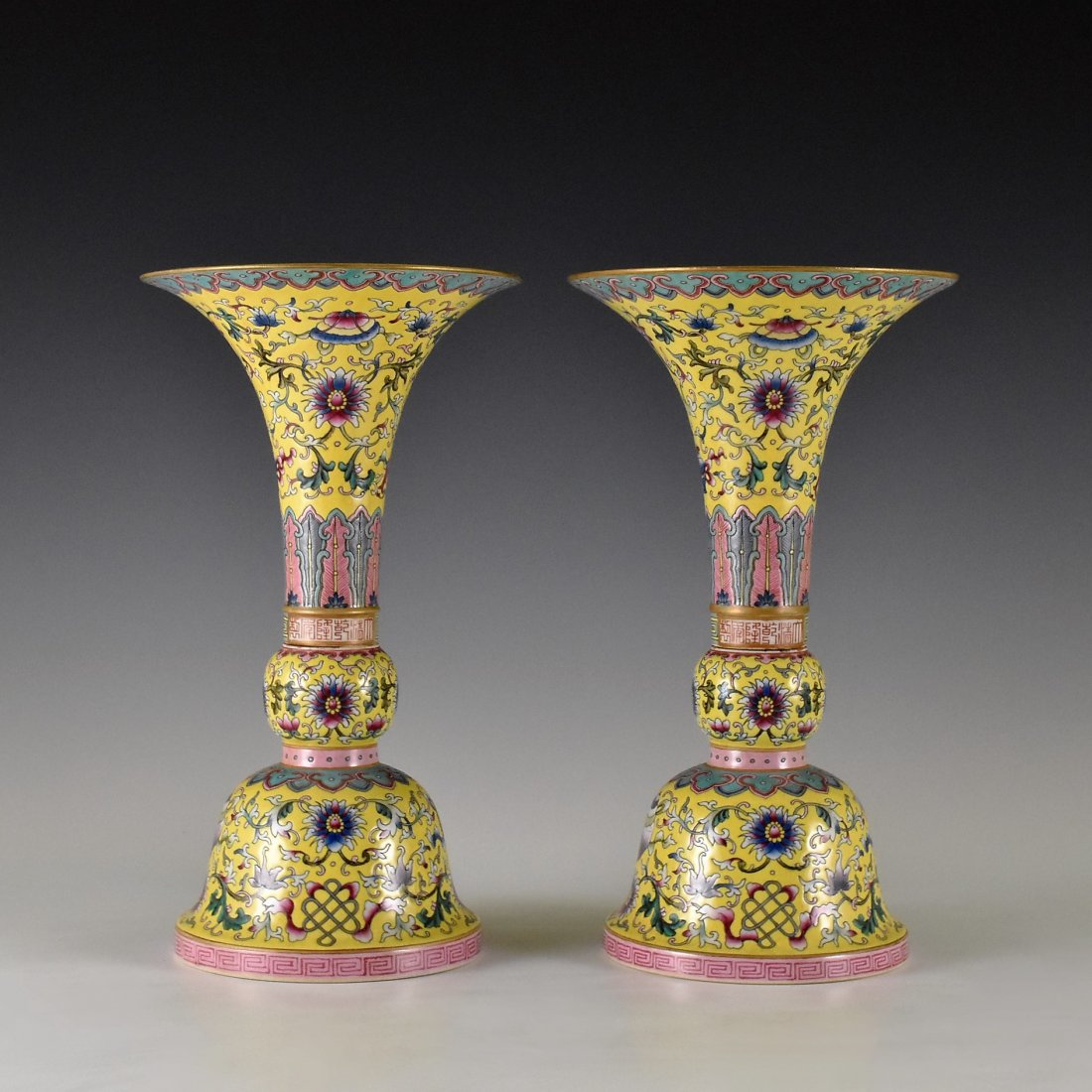 PAIR OF FAMILLE ROSE GU VASES ON YELLOW GROUND: The porcelain Chinese Gu porcelain vases, delicately potted with tall shaped vessel, bulbous belly, tall neck toward the over flared rim, raised upon splayed prominent foot base. Decorated in colorful