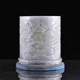 LANDSCAPE CARVED JADE BRUSH POT ON CUSHION STAND: Antique carved Chinese pale-celadon jade brush pot, of straight cylindrical body, elaborately deep carved in detail depicted continuous scene of group of figurines in various pursuit within waterside