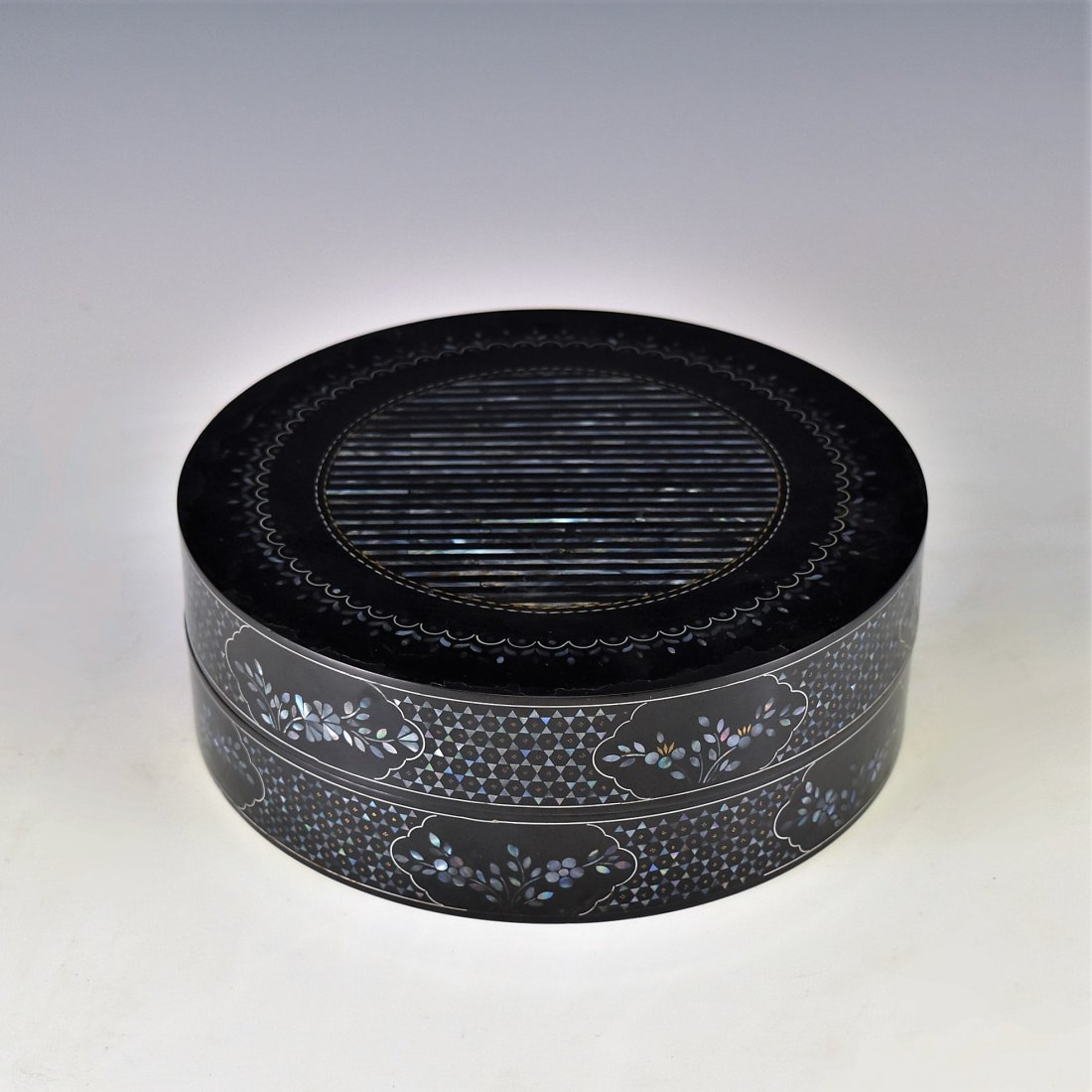 MOTHER OF PEARLS INLAID EBONY LACQUERED BOX: A antique Chinese fruit box crafted In form of a tapered straight cylindrical shape. The exterior decorated with mother of pearls inlaid with various geometrical patterns and floral motifs against ebo