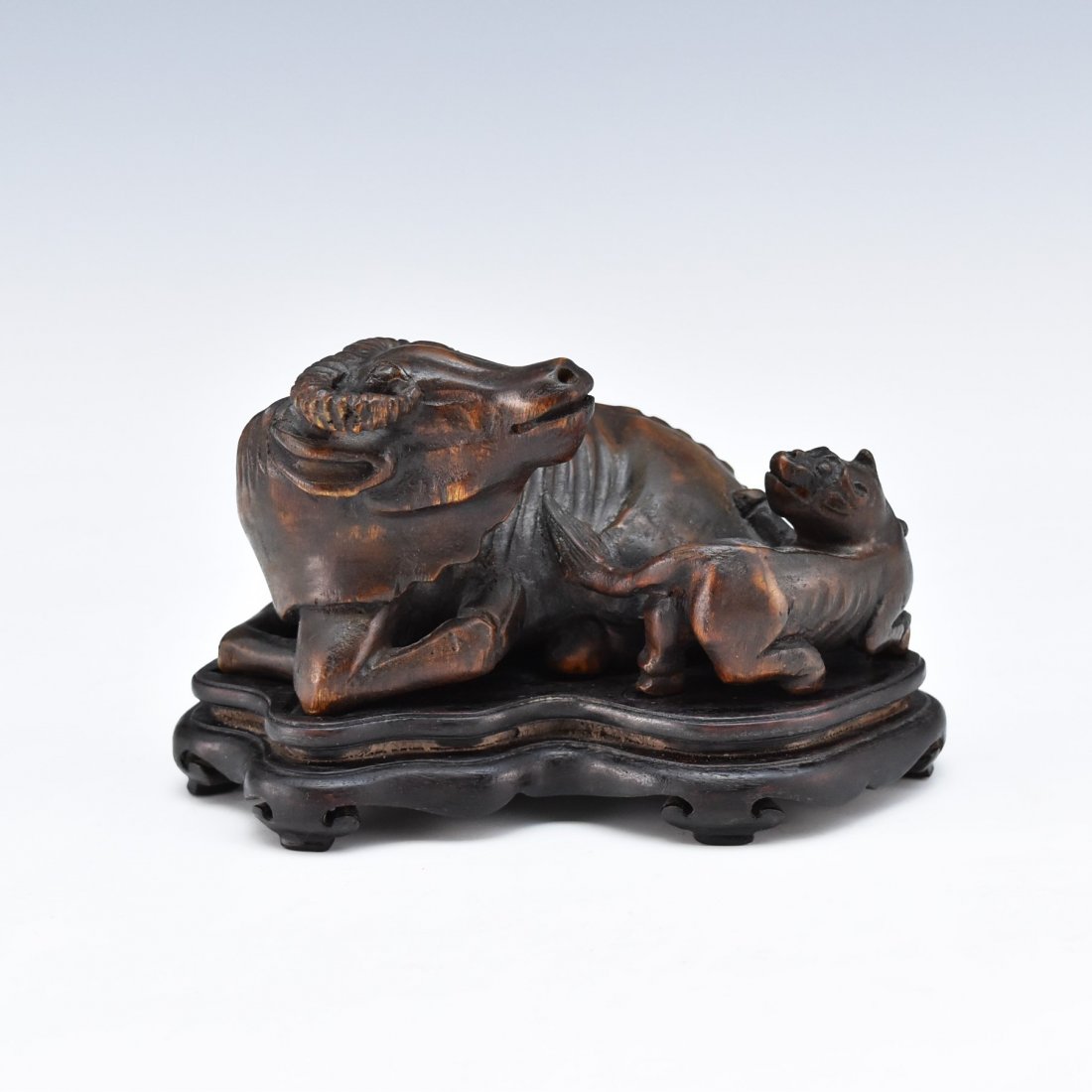 CARVED CHENXIANG WOOD OX AND DOG SCLUPTURE: The Carving sculpture crafted from a single piece valued ChenXiang wood (agarwood), recumbent an ox setting on its four legs in relaxing position, with head facing left shoulder, next to a meandering 