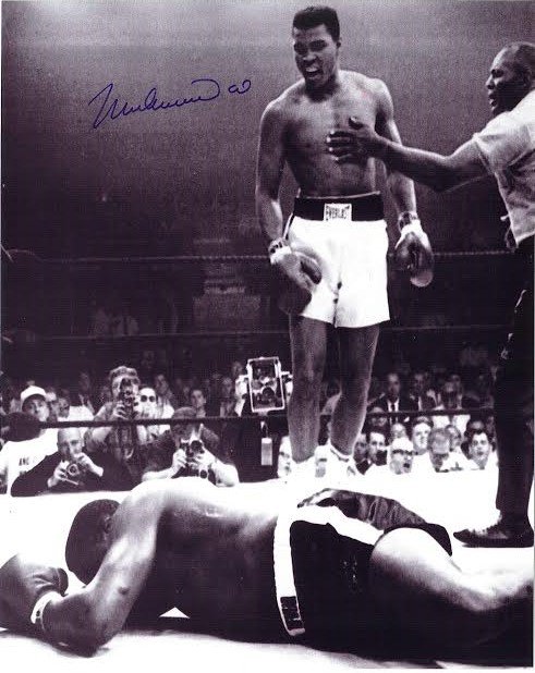 Muhammad Ali Signed Photograph AAU: Muhammad Ali Signed Photograph AAU F21414 this is a black and white photograph of Ali standing over an opponent and measures 8 x 10 inches.