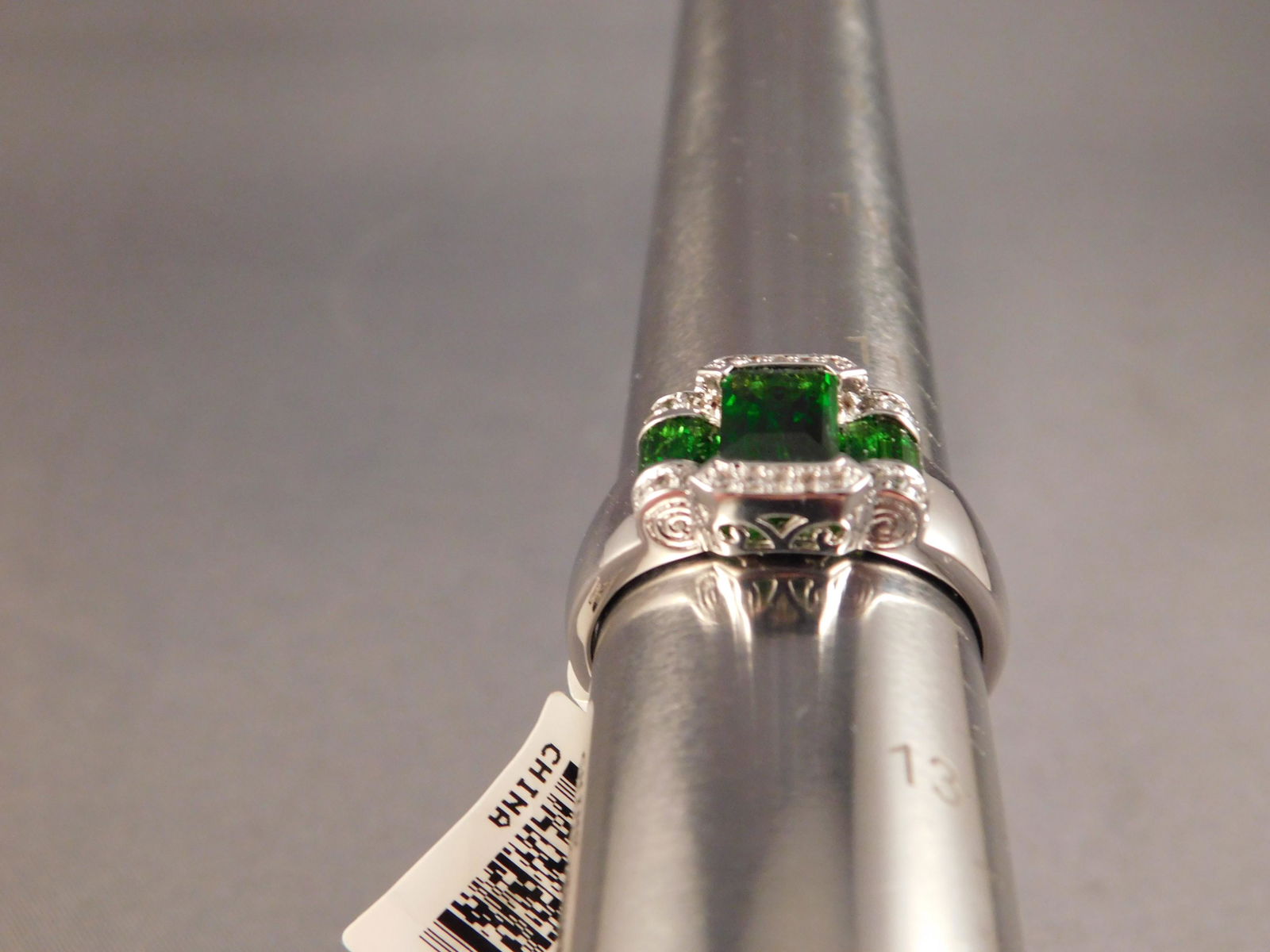 Sterling Silver Ring: Sterling silver ring with a green center stone and 2 small green accent stones. Has small white accent stones on the edge. Size 12. You are bidding at a live sale. Please read the terms and conditions