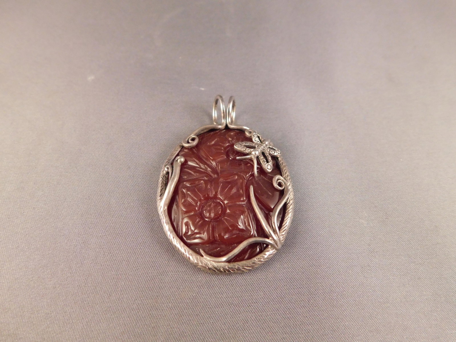 Sterling & Carved Carnelian Pendant: Large sterling silver carved carnelian floral pendant. Signed 925, BJ, China. You are bidding at a live sale. Please read the terms and conditions. We are offering appointment only no contact pick-up 