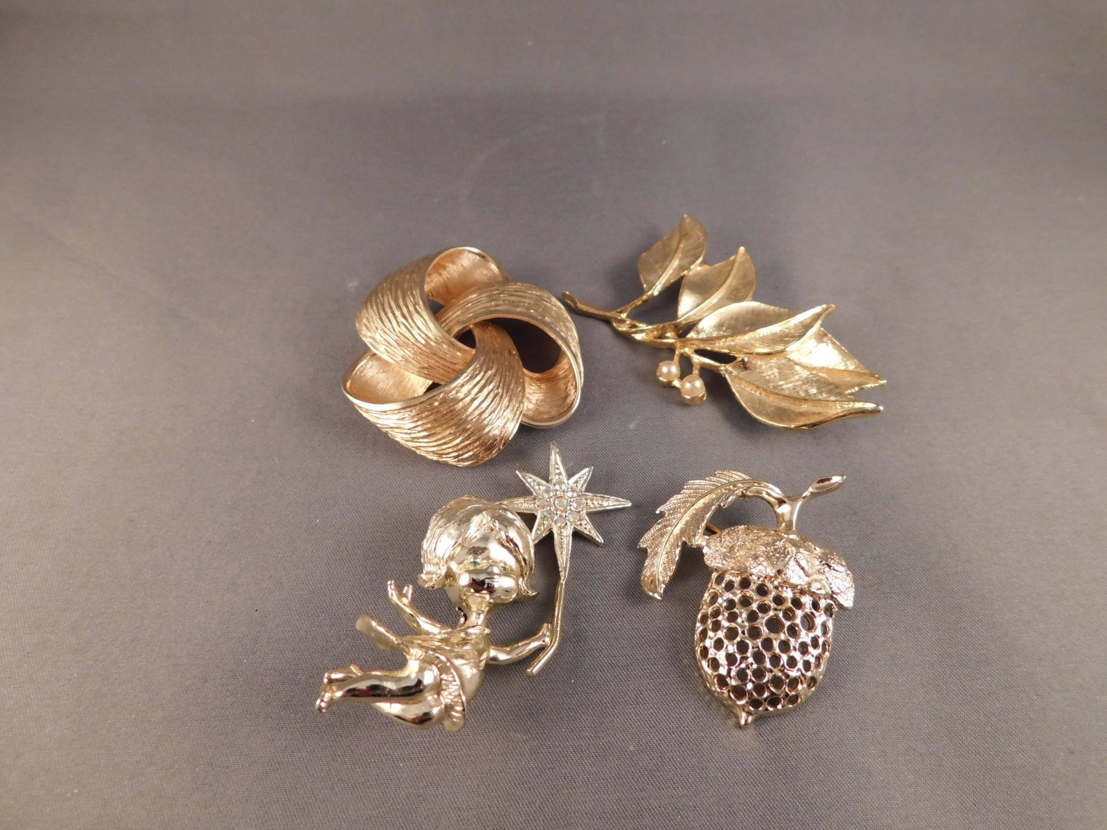 Group of 4 Pins: Lot of 4 pins. The first is a leaf style pin in gold tone signed ?Gerry S?, a girl with a wand signed Tanger II, an acorn signed Sara, and the last is a woven style, unsigned. They measure between 1 3