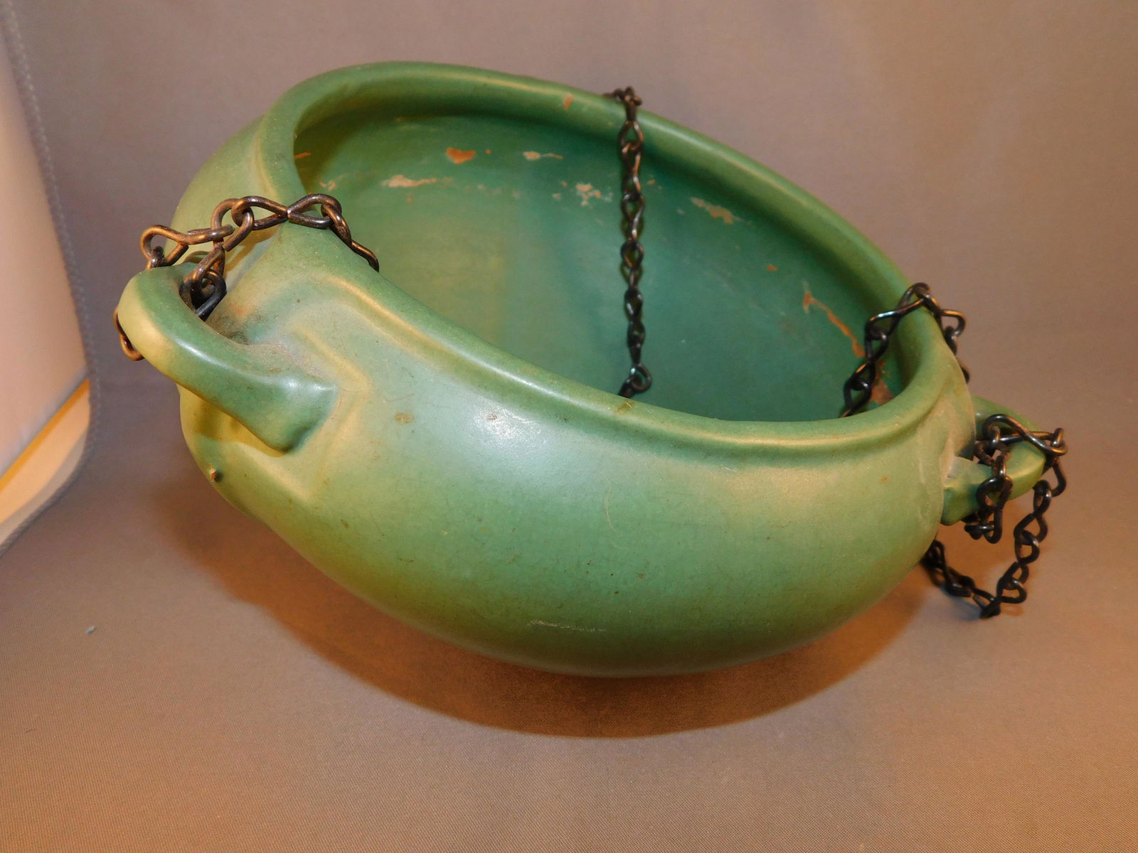 Roseville Matt Green Hanging Planter: Roseville art pottery matt green hanging planter. Measures approx. 4" tall x 7" in diameter. You are bidding at a live sale. Please read the terms and conditions. We are offering contactless pick up a