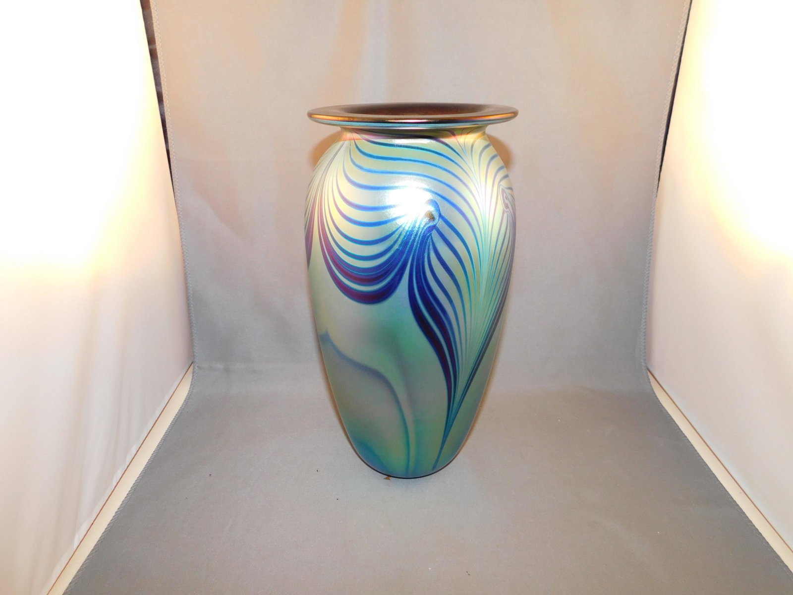 Eickholt Art Glass Vase: Art glass feather pulled tall vase, signed Eickholt 1995. Measures approx. 9" tall x 5" wide. You are bidding at a live sale. Please read the terms and conditions. We are offering no contact pick up a