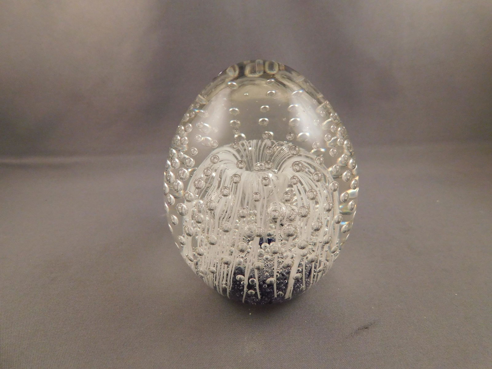 Art Glass Paperweight: Unsigned bubble controlled art glass paperweight. Measures approx. 3 1/2" tall x 2 3/4" wide. You are bidding at a live sale. Please read the terms and conditions. We are offering no contact pick up a