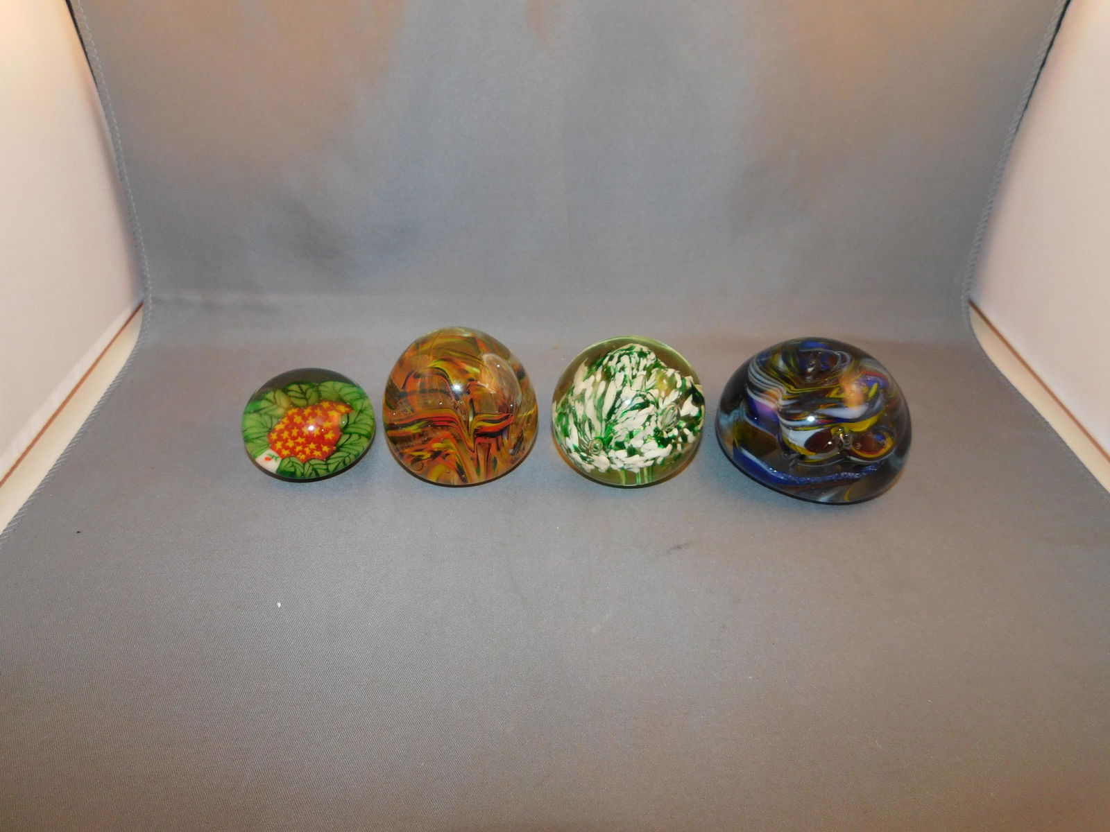 4 Art Glass Paperweights: Lot of 4 unsigned art glass paperweights. Measures approx. 1 1/4" - 2" tall x 1 3/4" - 2 1/2" wide. You are bidding at a live sale. Please read the terms and conditions. We are offering no contact pic
