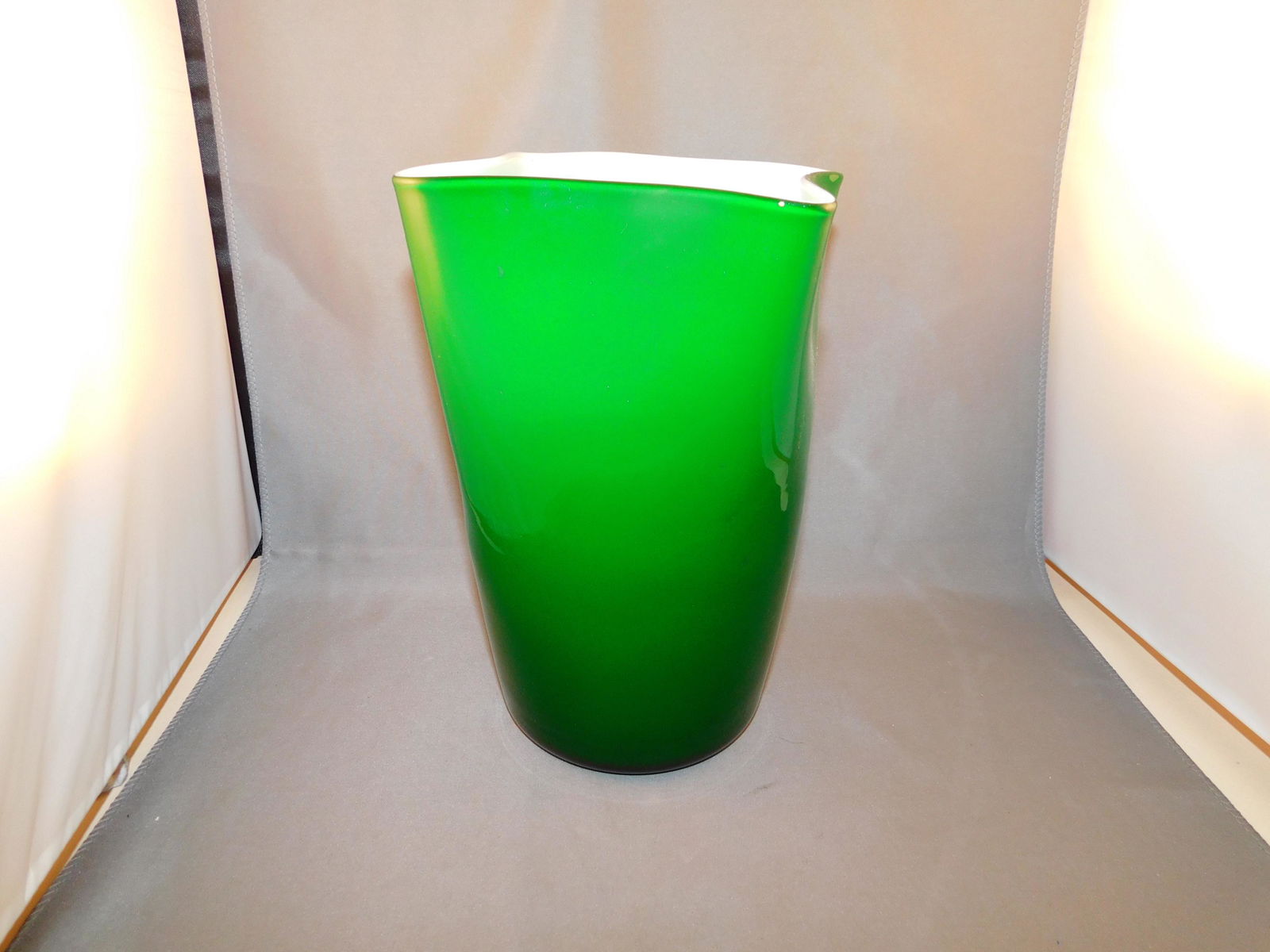 Art Glass Vase: Hand blown art glass vase in green and white. Measures approx. 8" tall x 6 1/4" wide. You are bidding at a live sale. Please read the terms and conditions. We are offering no contact pick up at our So