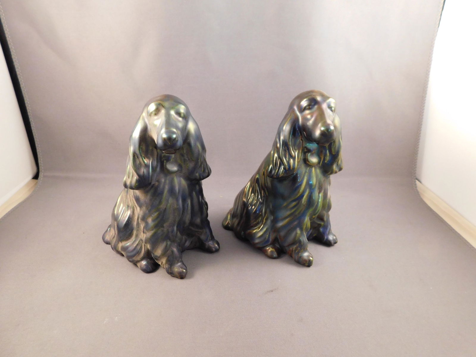 Pair of Zsolnay Dogs: Pair of iridescent purple Zsolnay dogs. Measures approx. 4 3/4" tall x 3 1/2" wide. You are bidding at a live sale. Please read the terms and conditions. We are offering no contact pick up at our Sout