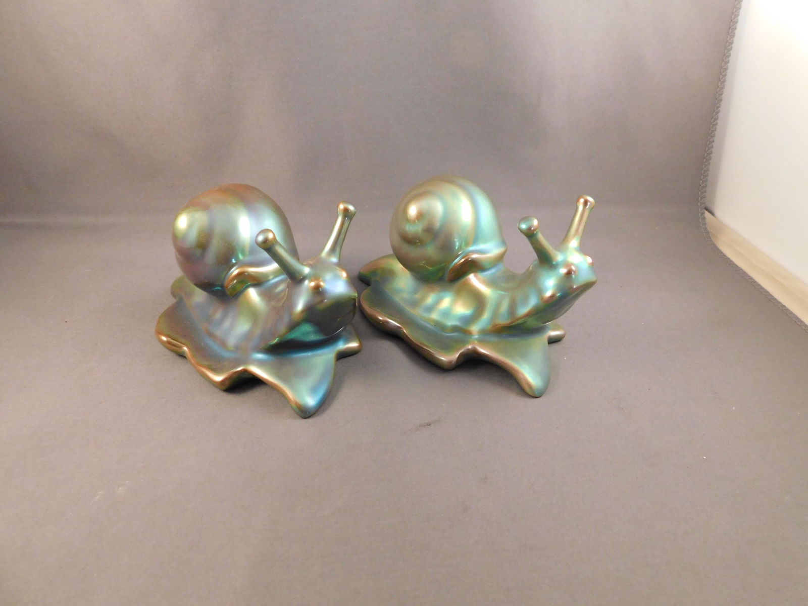 Pair of Zsolnay Snails: Pair of blue iridescent Zsolnay snails. Measures approx. 2 1/2" tall x 4 1/2" wide. You are bidding at a live sale. Please read the terms and conditions. We are offering no contact pick up at our Sout