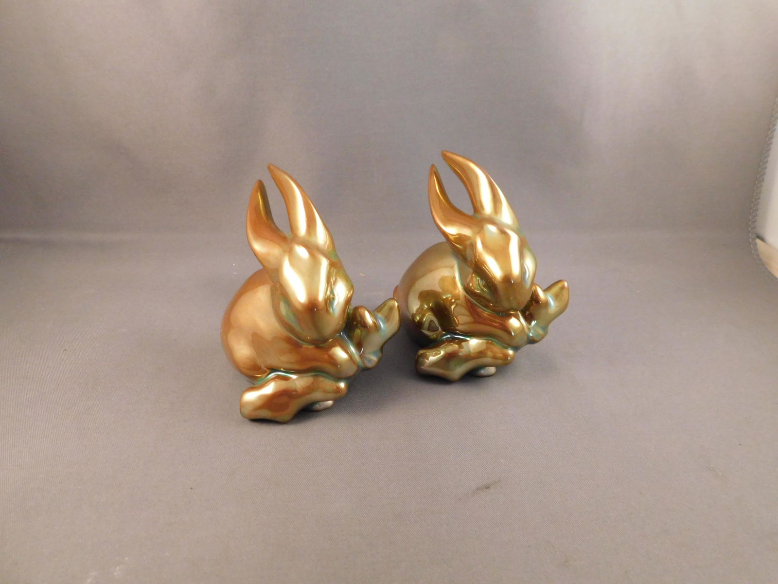 Pair of Zsolnay Rabbits: Pair of gold iridescent Zsolnay rabbits. Measures approx. 3" tall x 2 1/4" wide. You are bidding at a live sale. Please read the terms and conditions. We are offering no contact pick up at our South B