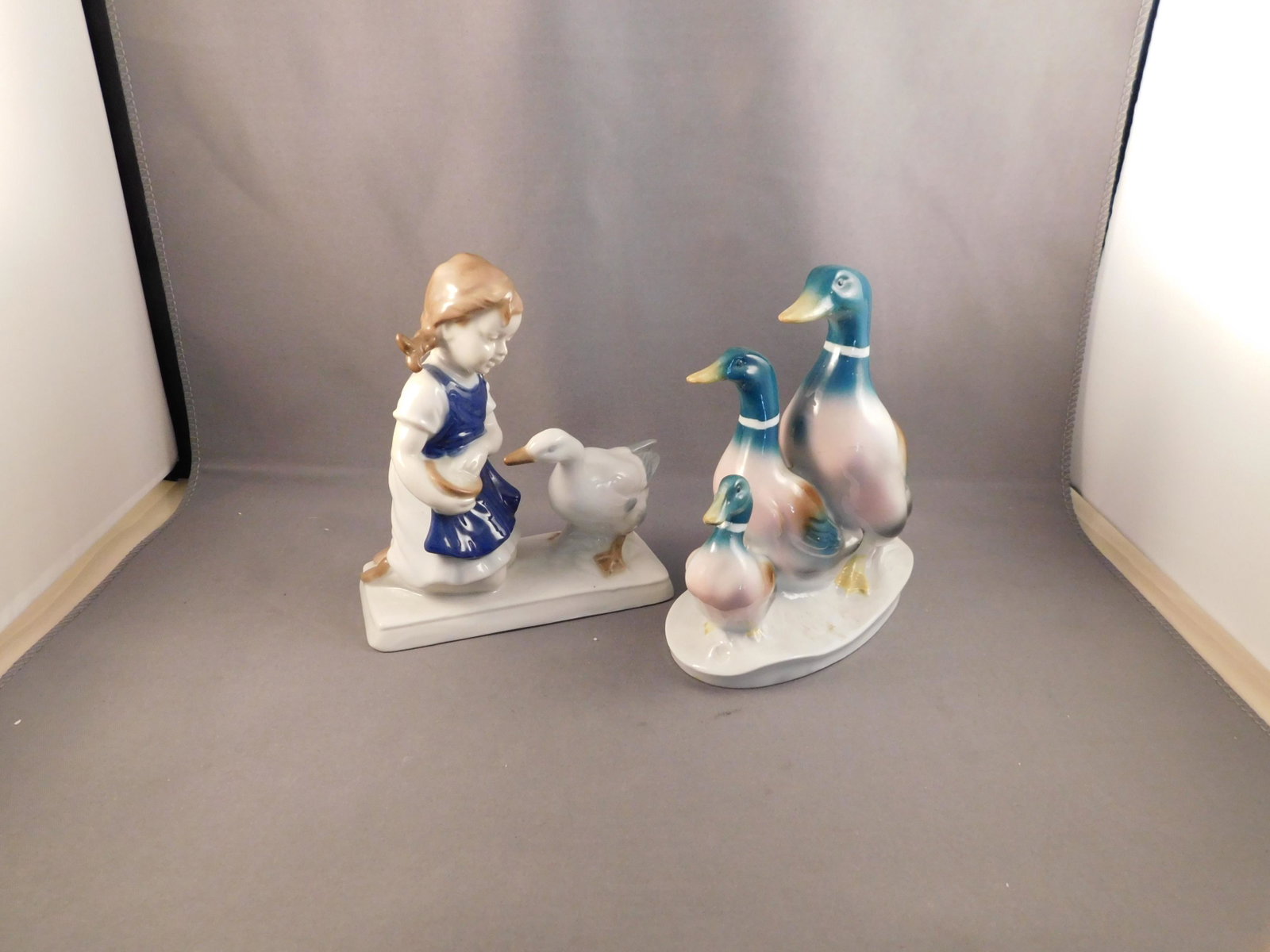 Lot of 2 Figurines: Lot of 2 figurines. The first is a girl with a goose. Marked with crossed swords - 1859, hand painted. Second is 3 geese marked with an S and a crown. Germany. Measures approx. 5" tall. You are biddin