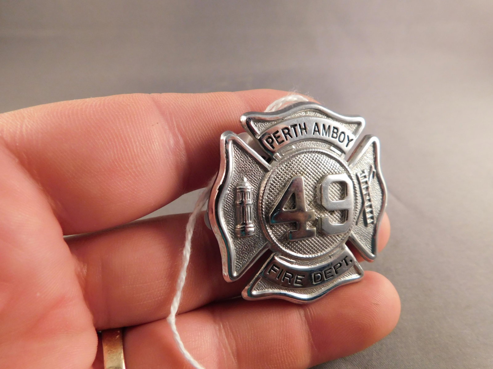 Perth Amboy Fire Badge: Silver tone Perth Amboy Fire Dept badge with 49 in the center. Measures approx. 1 3/4" long. You are bidding at a live sale, please read the terms and conditions. We are offering contact-less pick ups