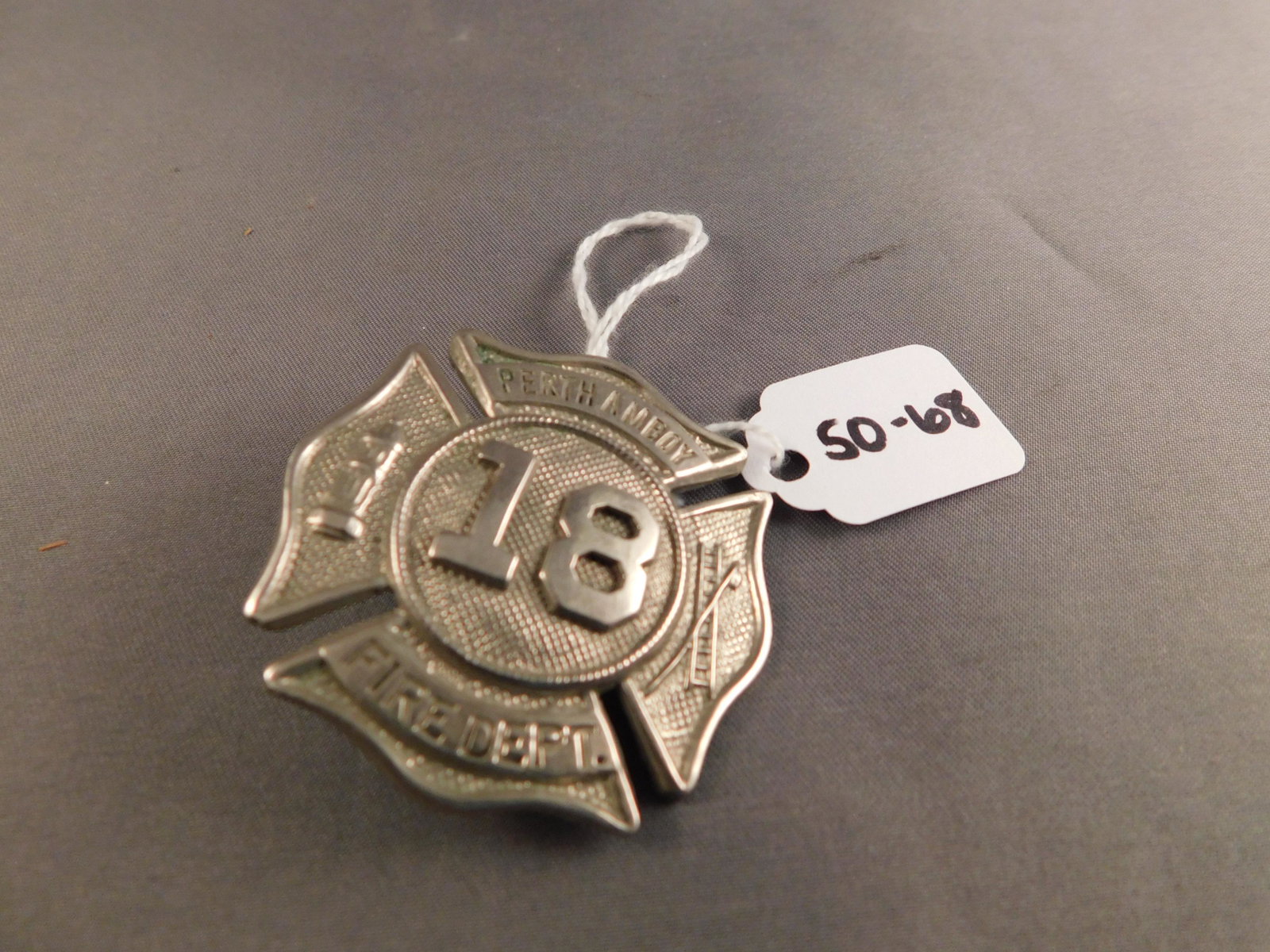 Perth Amboy Fire Badge: Silver tone Perth Amboy Fire Dept badge with 18 in the center. Measures approx. 1 3/4" long. You are bidding at a live sale, please read the terms and conditions. We are offering contact-less pick ups