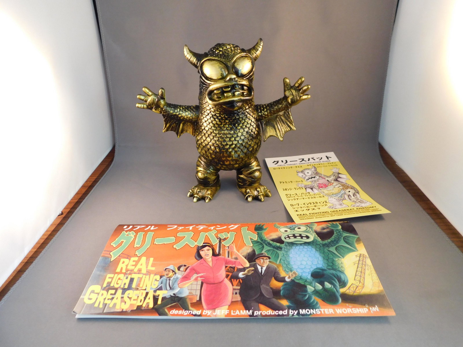 Japanese Vinyl Greasebat, Gold: Japanese Vinyl real fighting Greasebat, gold. Signed Jeff Lamm, 2010. Measures approx. 6 1/2" tall. You are bidding at a live sale, please read the terms and conditions. We are offering contact-less p