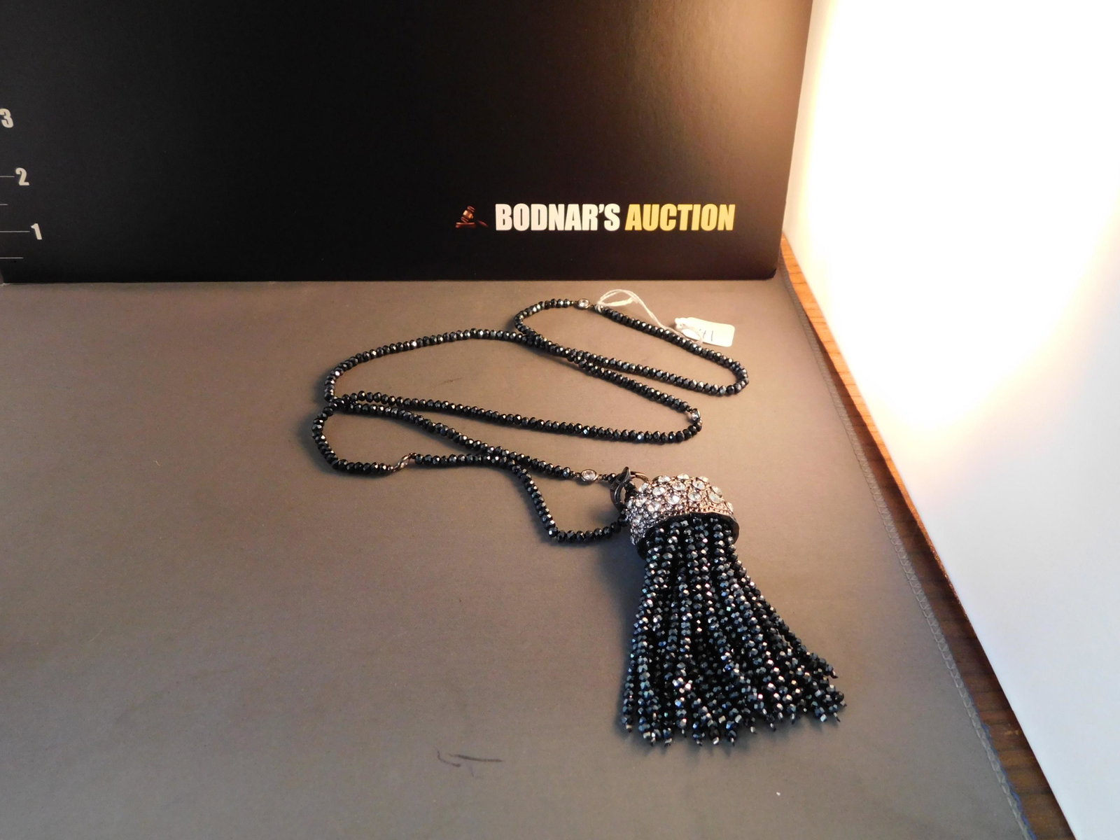 Joan Boyce Tassel Necklace: Joan Boyce blue stone & crystal tassel necklace. Marked on bale. Measures 36". You are bidding at a live sale. Please read the terms and conditions. We are offering no contact pick up at our South Bru