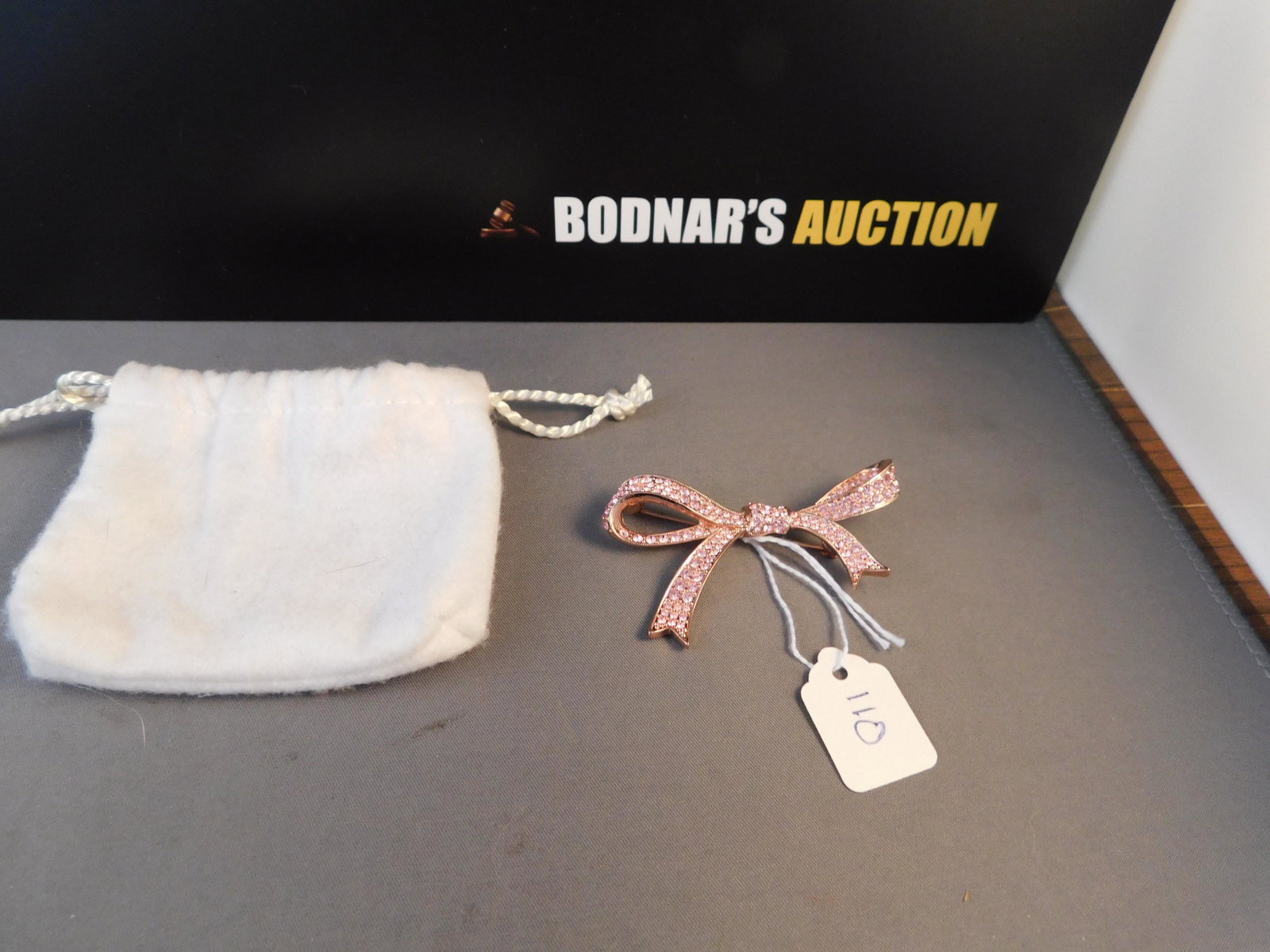 KJL Pink Crystal Bow Pin: KJL (Kenneth J Lane) rose gold tone bow pin set with crystals. Marked on back. Measures 2 1/2". You are bidding at a live sale. Please read the terms and conditions. We are offering no contact pick up