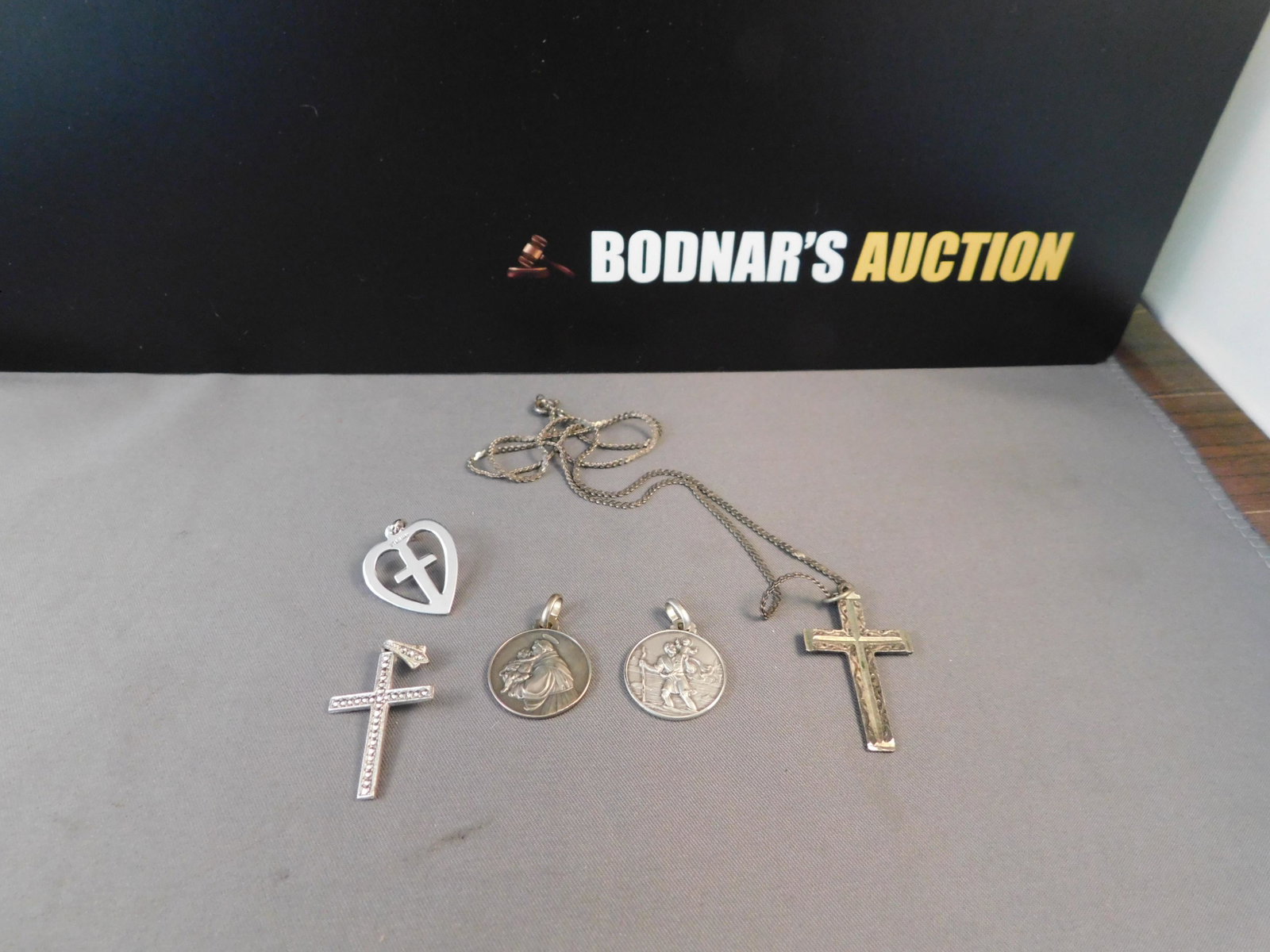 Lot Sterling Crosses Religious Medals: Lot of sterling silver religious medals and crosses. Some have marcasite accents. Measures 5/8" to 1 1/8". All are marked. Chain measures 17" are bidding at a live sale. Please read the terms and cond