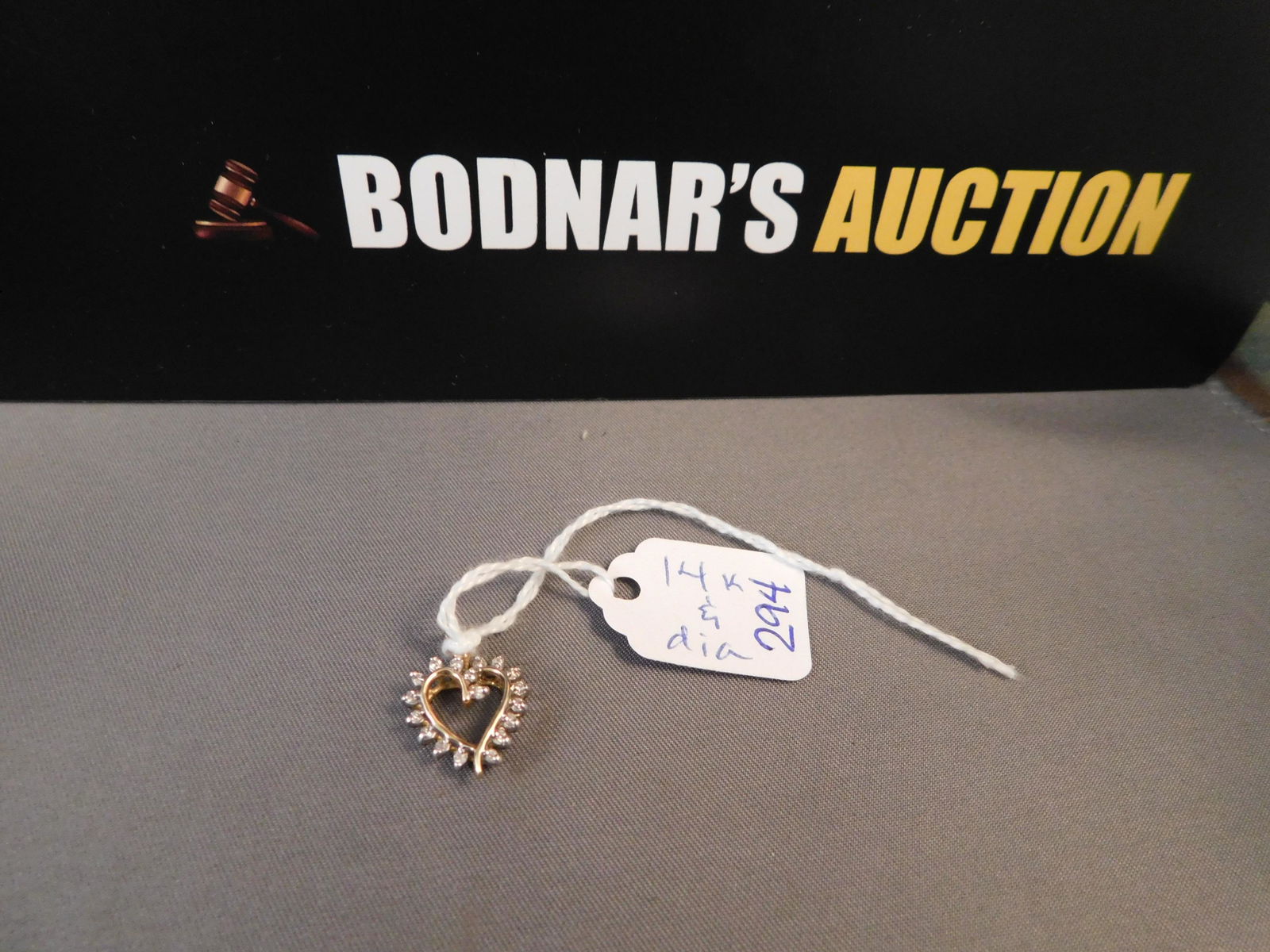 14K Heart Diamond Pendant: 14K yellow gold heart pendant with diamonds. Marked on back but can't read mark. Tests as 14K. Measures 3/4". You are bidding at a live sale. Please read the terms and conditions. We are offering no c