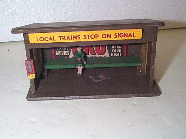 Nice wooden sheltered train stop with advertizing a: Nice wooden sheltered train stop with advertizing and woman sitting on bench Pencil notation on bottom: 200 Measures 2.5" tall by 4.5" long by 2.5" wide In excellent condition Buyer to pay $15.00 if y