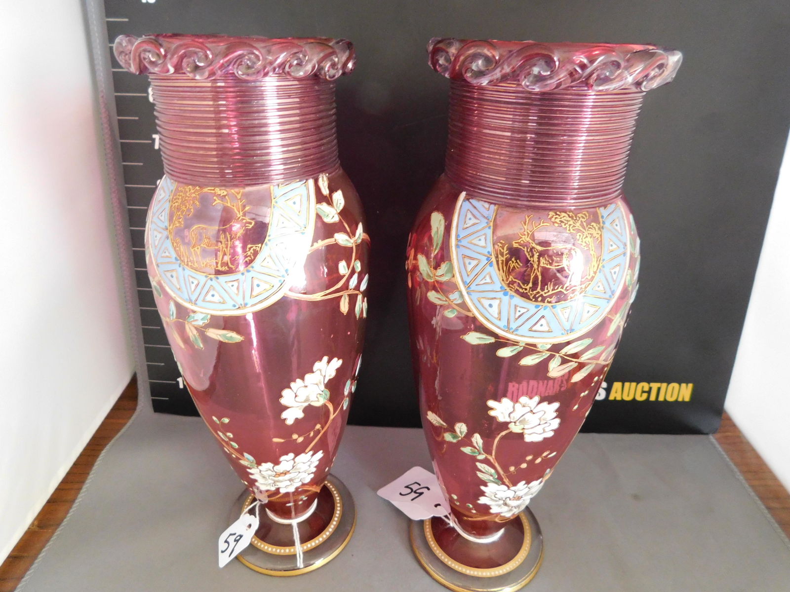 Pair of Victorian Cranberry Enamel Painted Vases: Pair of Victorian Cranberry Enamel Painted Vases with Gold. Ribbon glass with glass decorated cap. Measures approx. 9.5" tall. You are bidding at a live sale, please read the terms and conditions. We