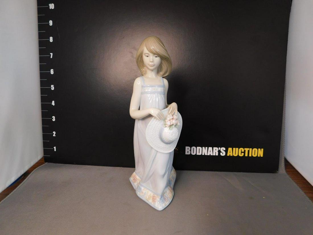 Lladro Figurine of Girl Holding Hat: Lladro Figurine 5643 - Girl Holding hat with Flowers. Measures 8" tall. You are bidding at a live sale, please read the terms and conditions. We are offering contact-less pick ups at our South Brunswi